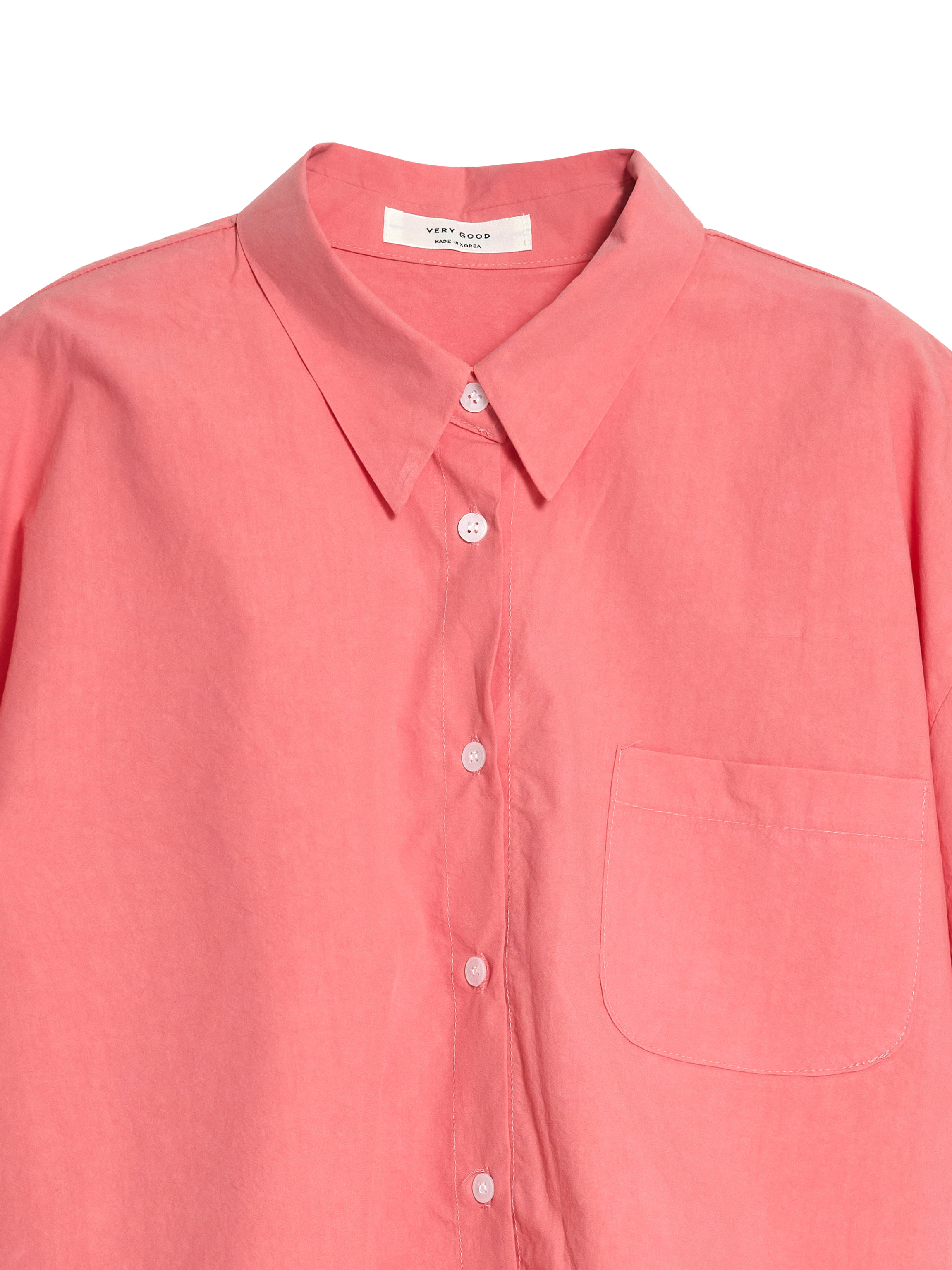 Product detail shot of the oversized short-sleeve shirt that highlights the pointed collar and the buttons.