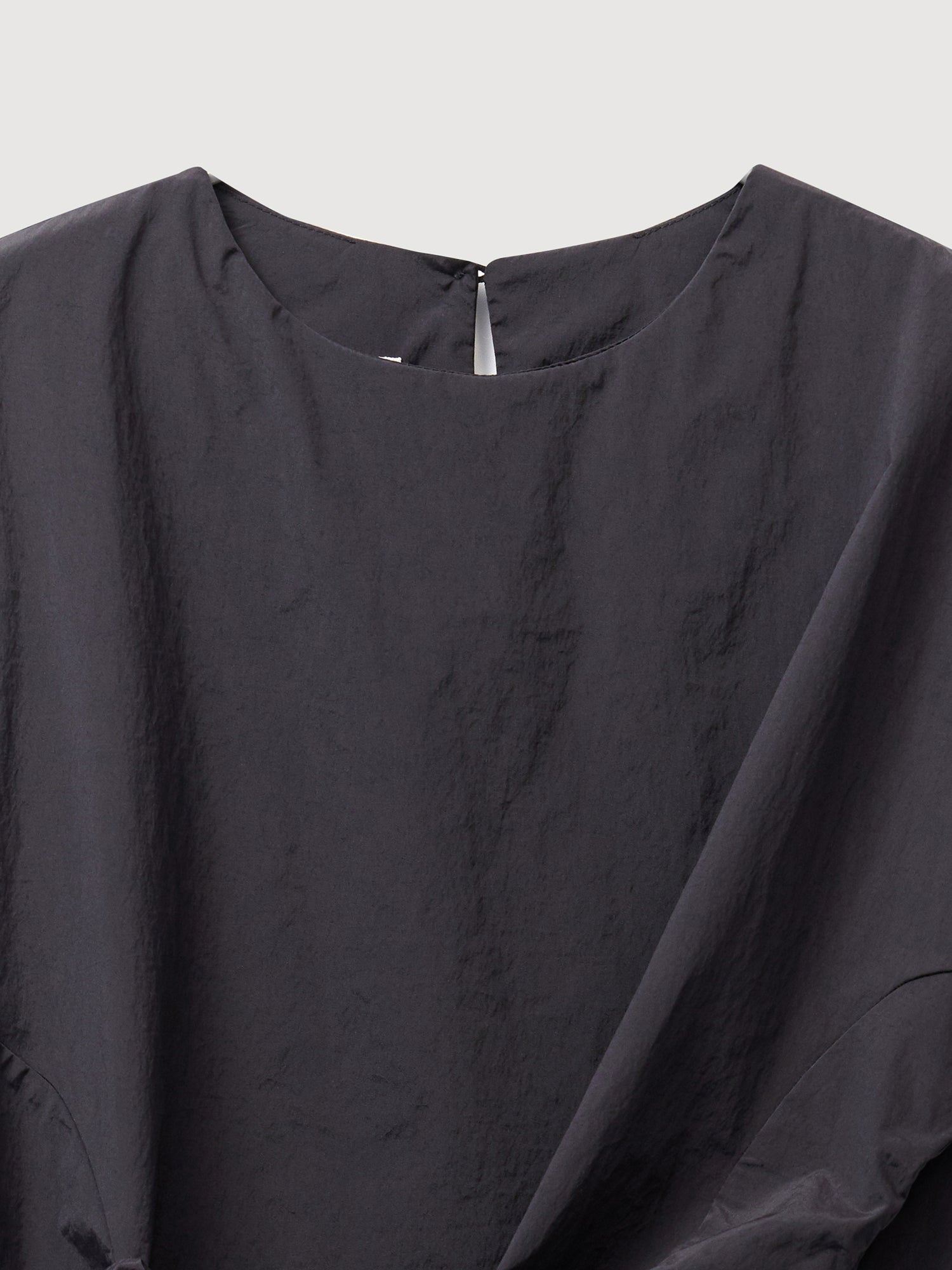 A close-up shot of the black front wrap blouse focusing on the fabric and neckline of the blouse.