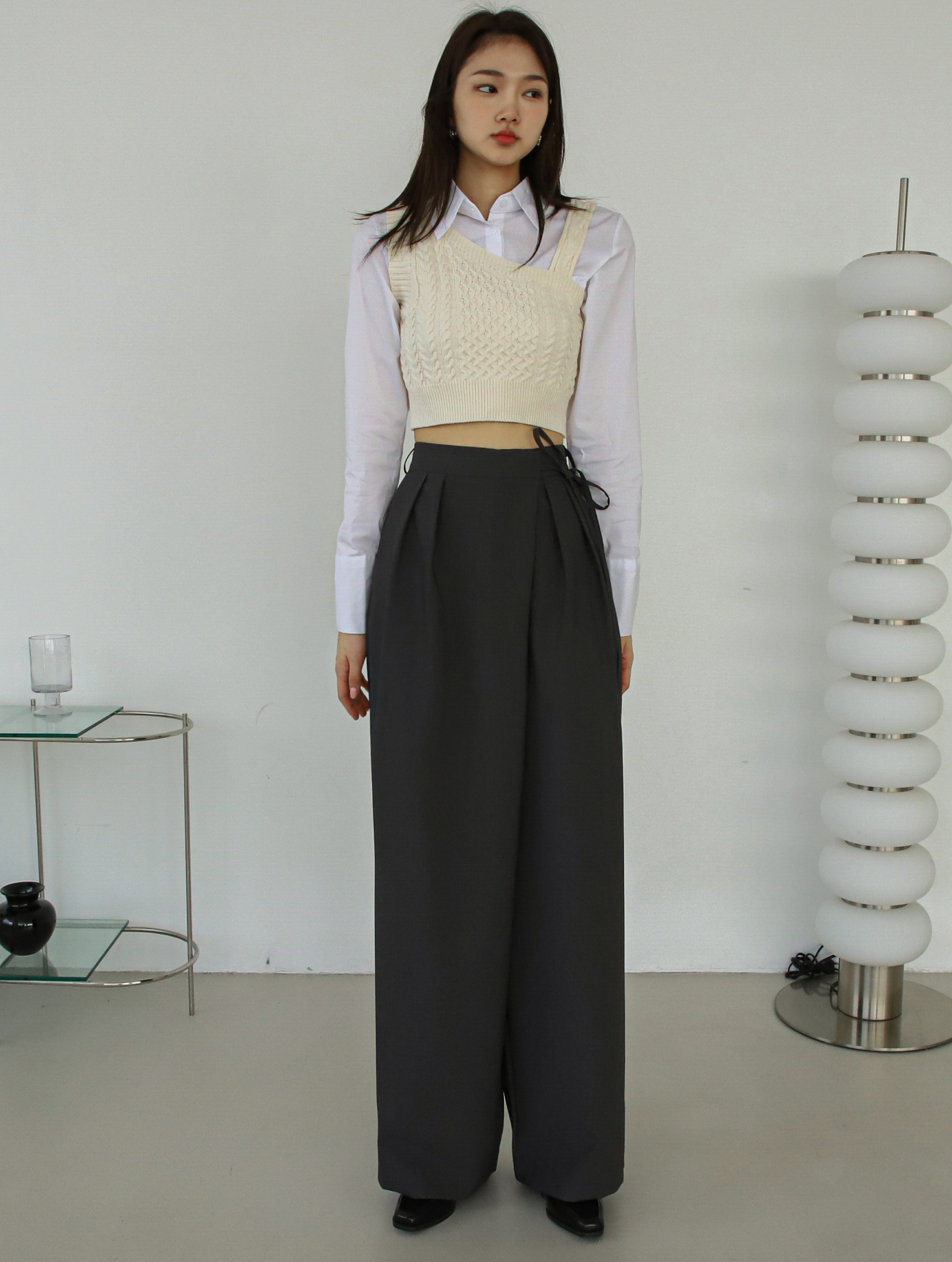 A close-up image of a model standing wearing a belted-tie pants.