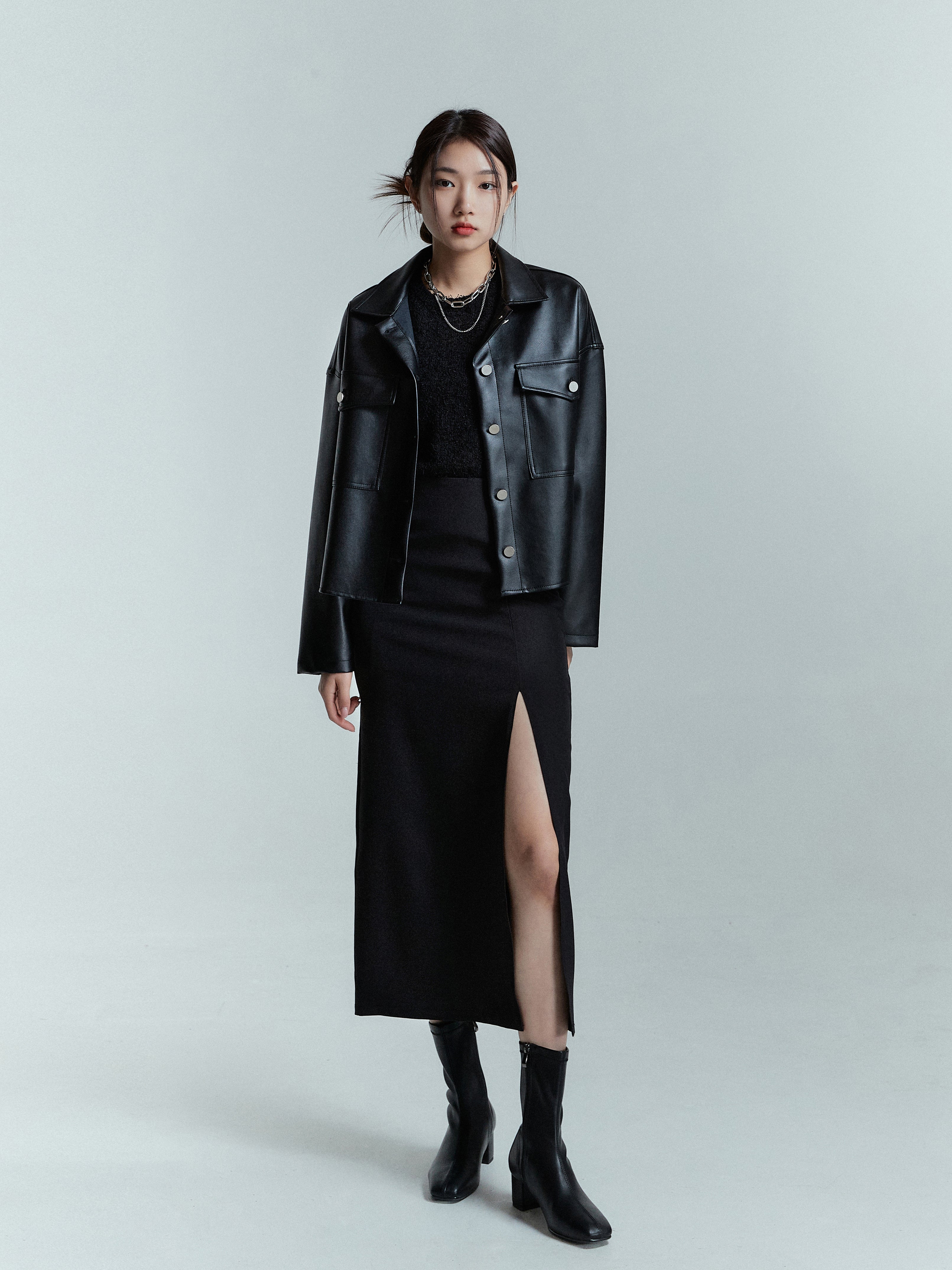 Capture a stylish full-length shot of the model exuding confidence in a sleek black leather jacket paired with a chic slit-cut skirt.