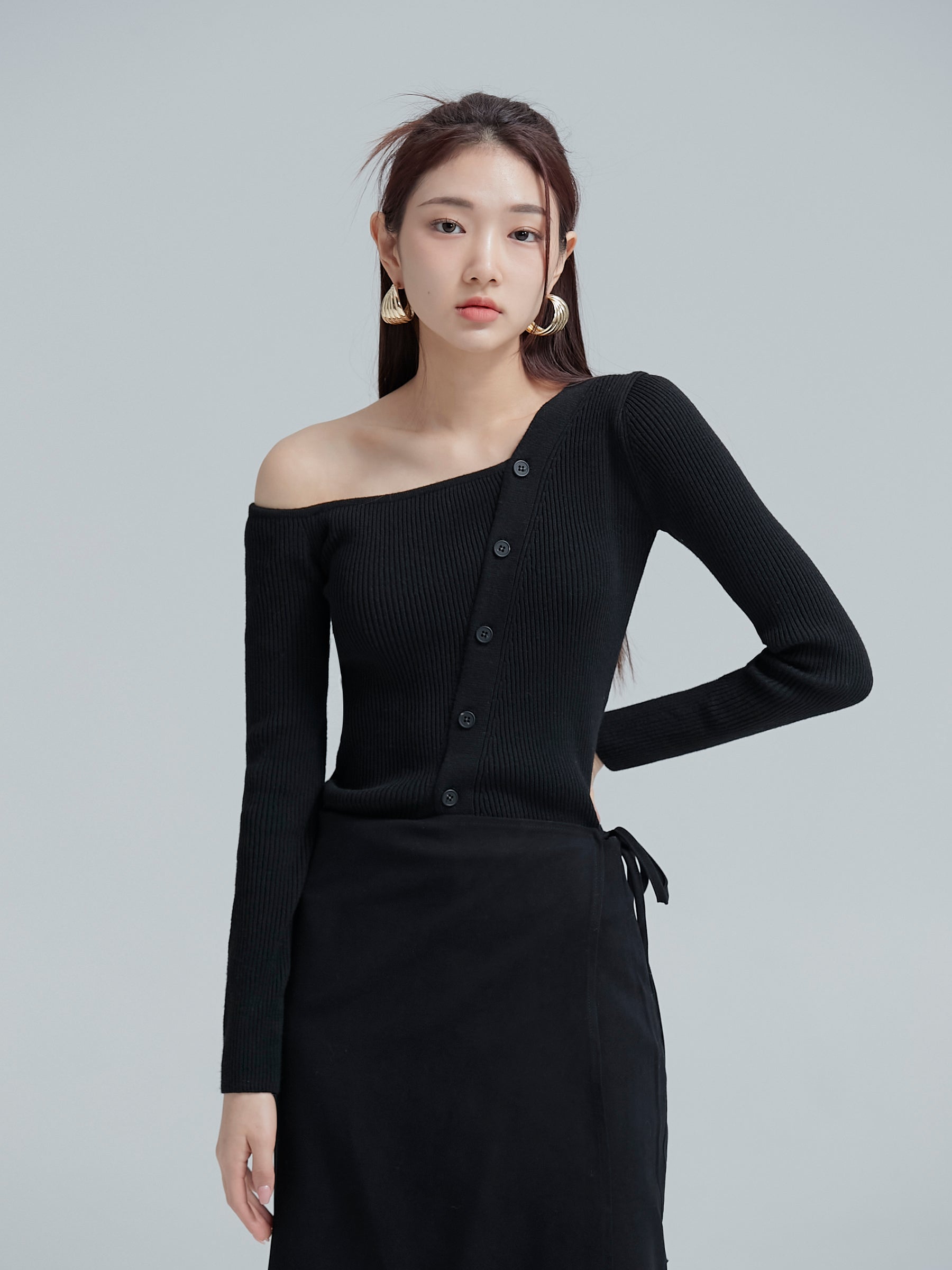 Front view of the model wearing the black button off shoulder top to showcase its chic style of the korean street fashion.