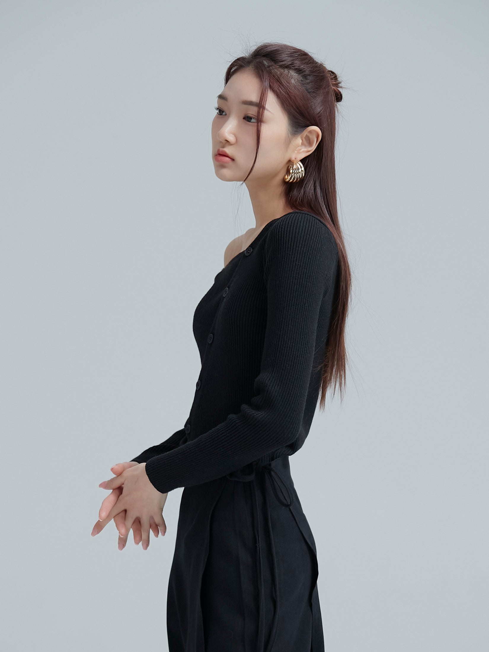 A side angle of the model wearing the black button off shoulder top showing the side fitting of the top.