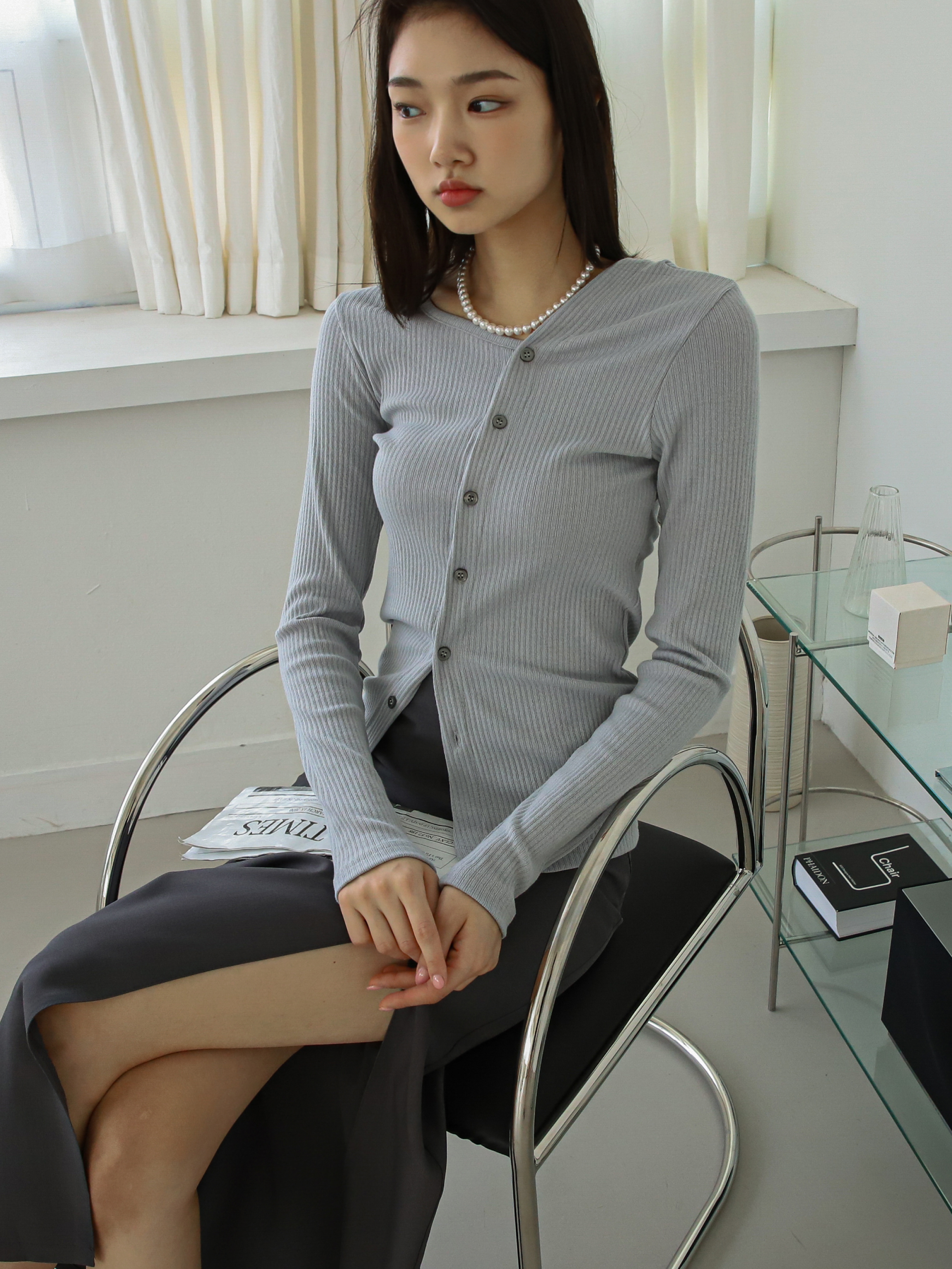 A tilted angle of the model wearing the gray buttoned up sweatshirt matching it with the slit midi skirt.