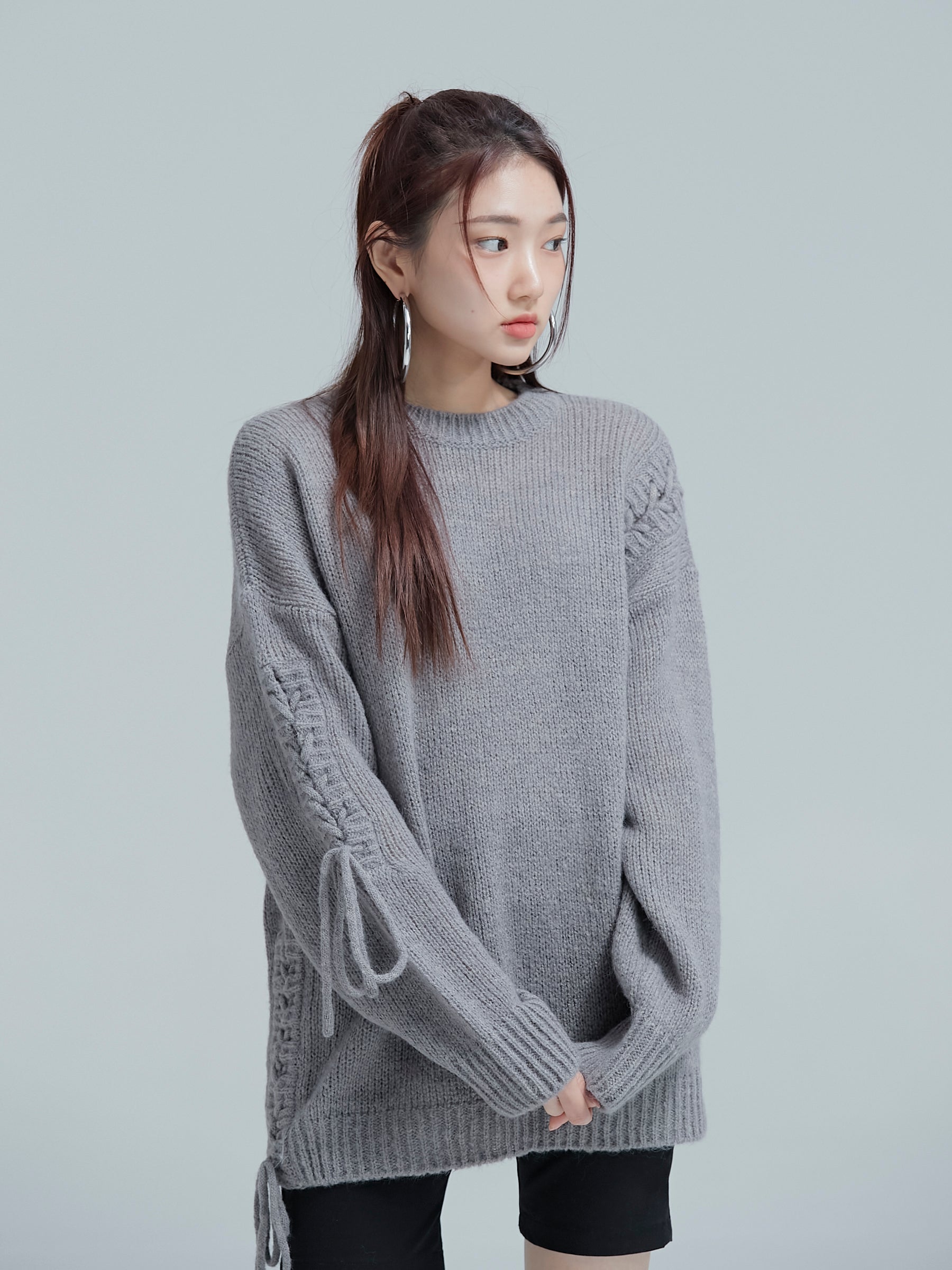 Close-up shot of the model glancing to the side while wearing the cable tie sweater to show its korean street style.