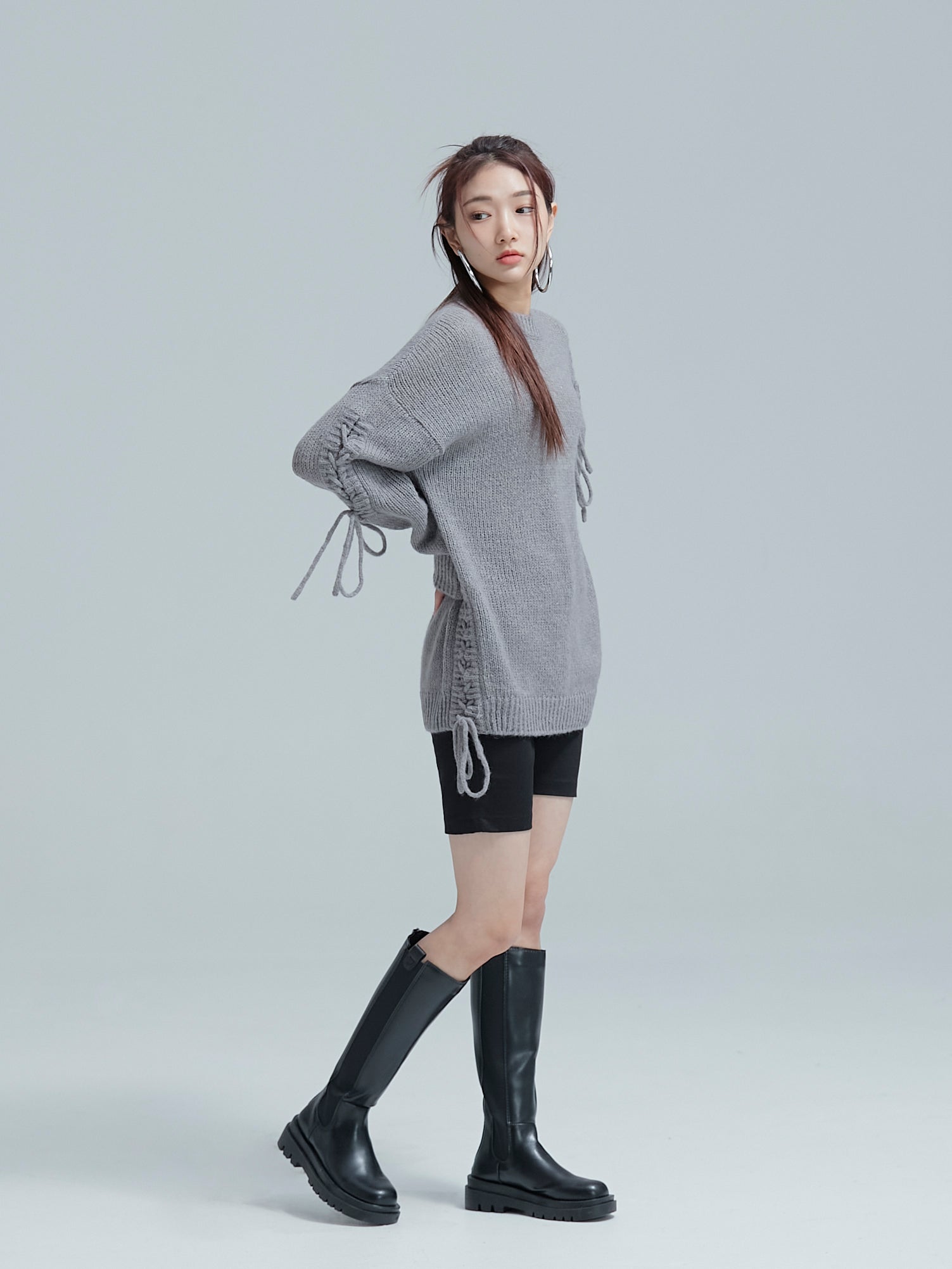 A side view of the model wearing the cable tie sweater to show its intricate details of the cable tie designs.