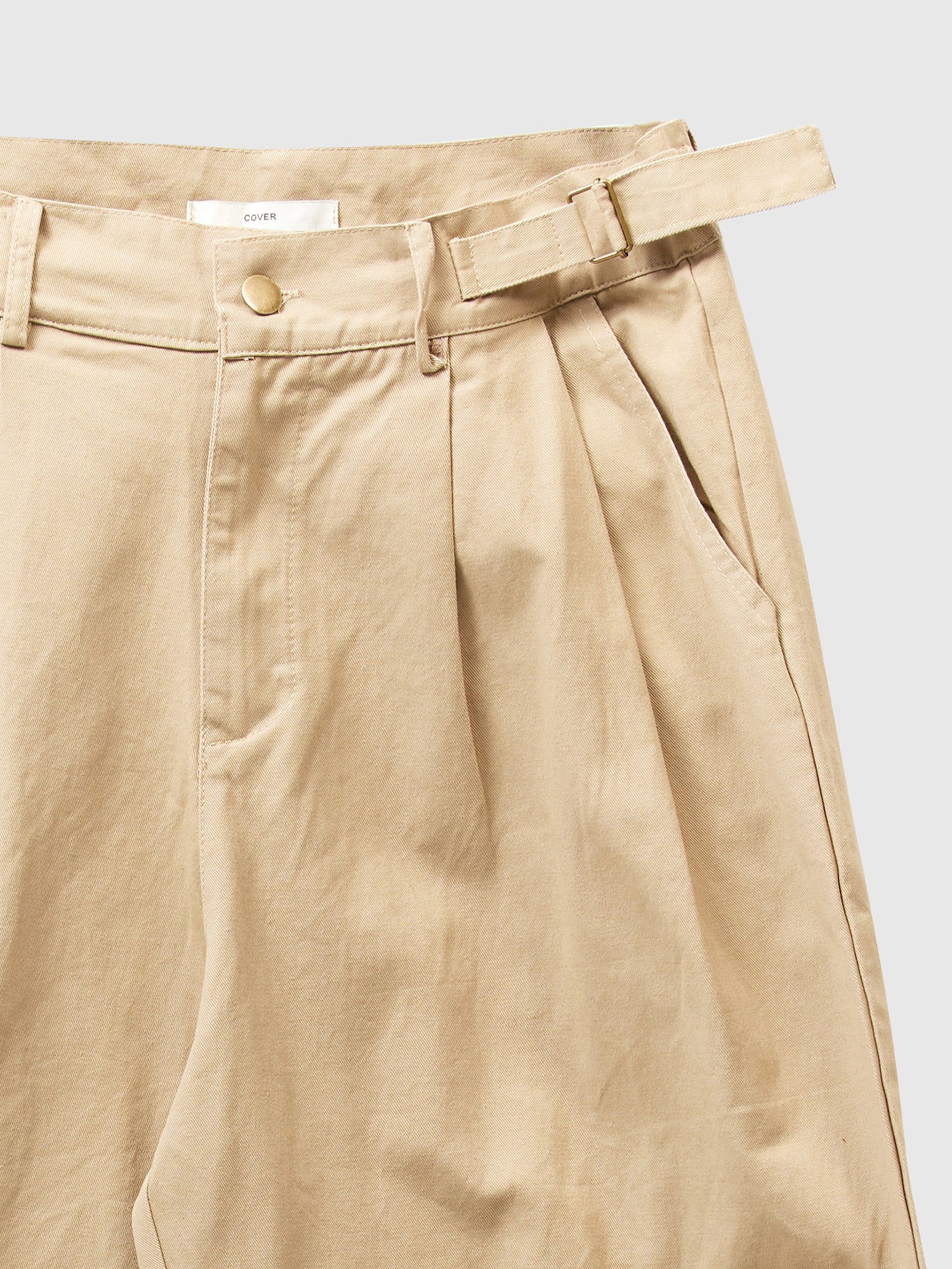 Zoomed-in shot at the light beige cargo pants, highlighting the fabric and intricate front seam design.