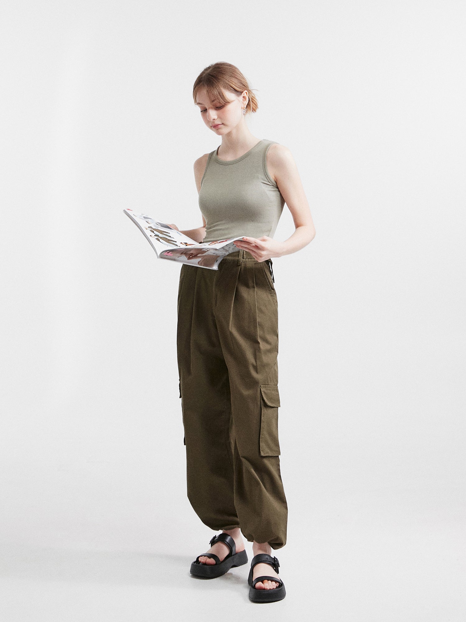 A side-angle view of the model wearing the sleeveless tank top casting a glance at the magazine.