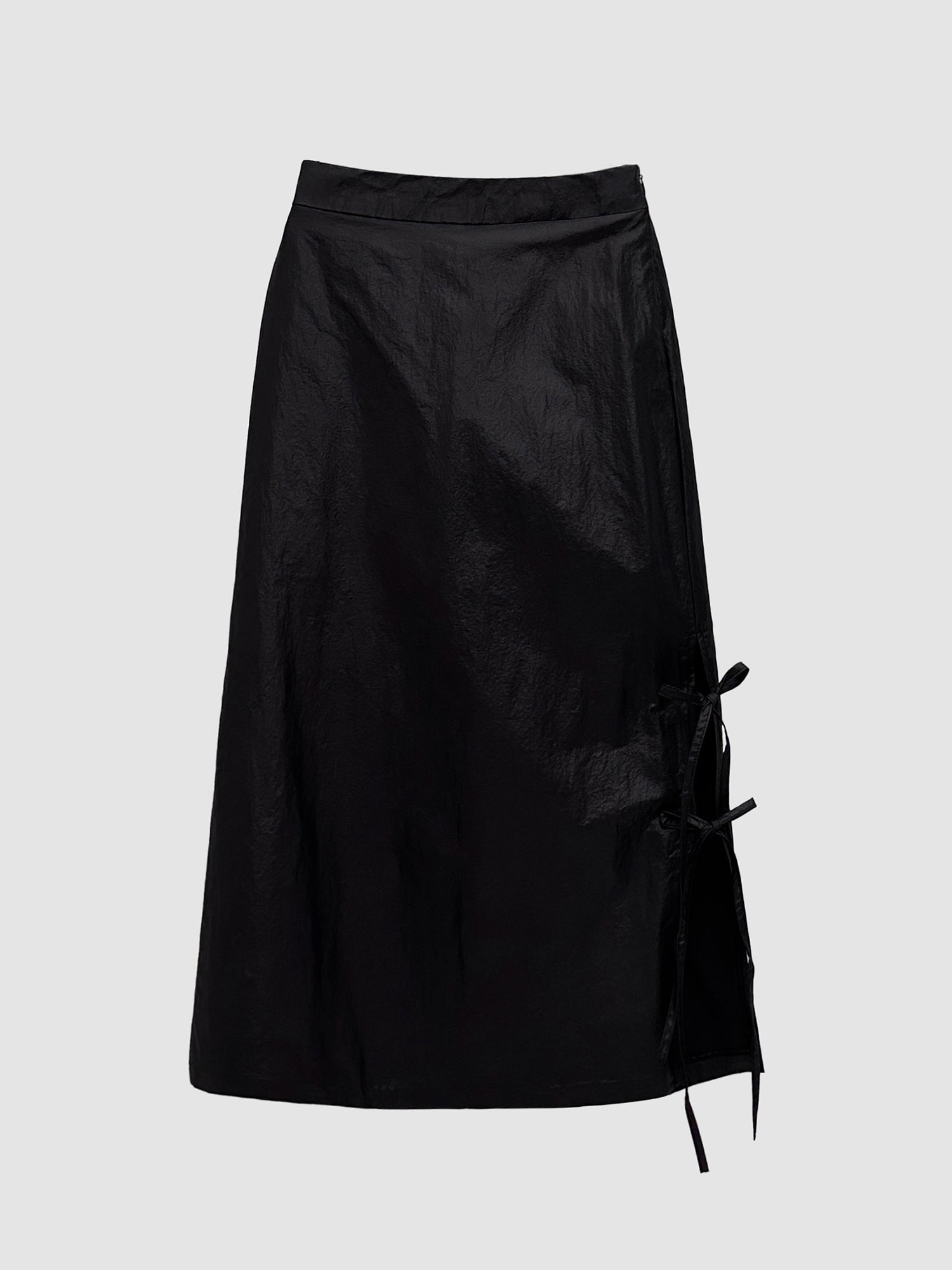 Front detailed view of the black coated midi skirt with gray backdrop.