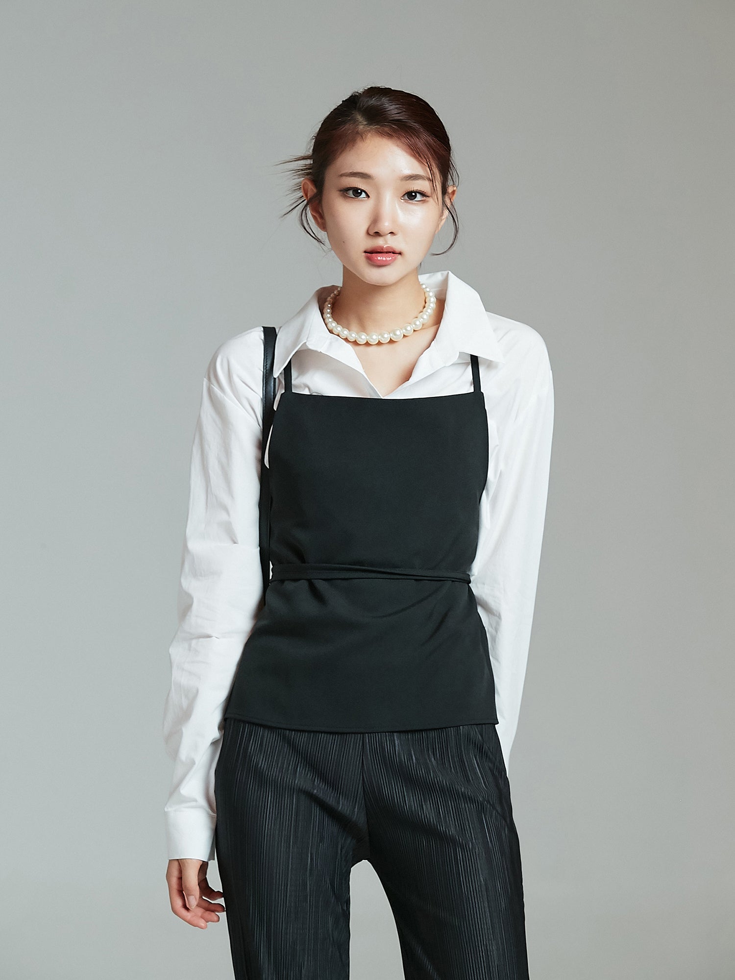 Front view of the model wearing the white coated shirt with pockets and matching it with strappy top to highlight its korean street fashion look.  