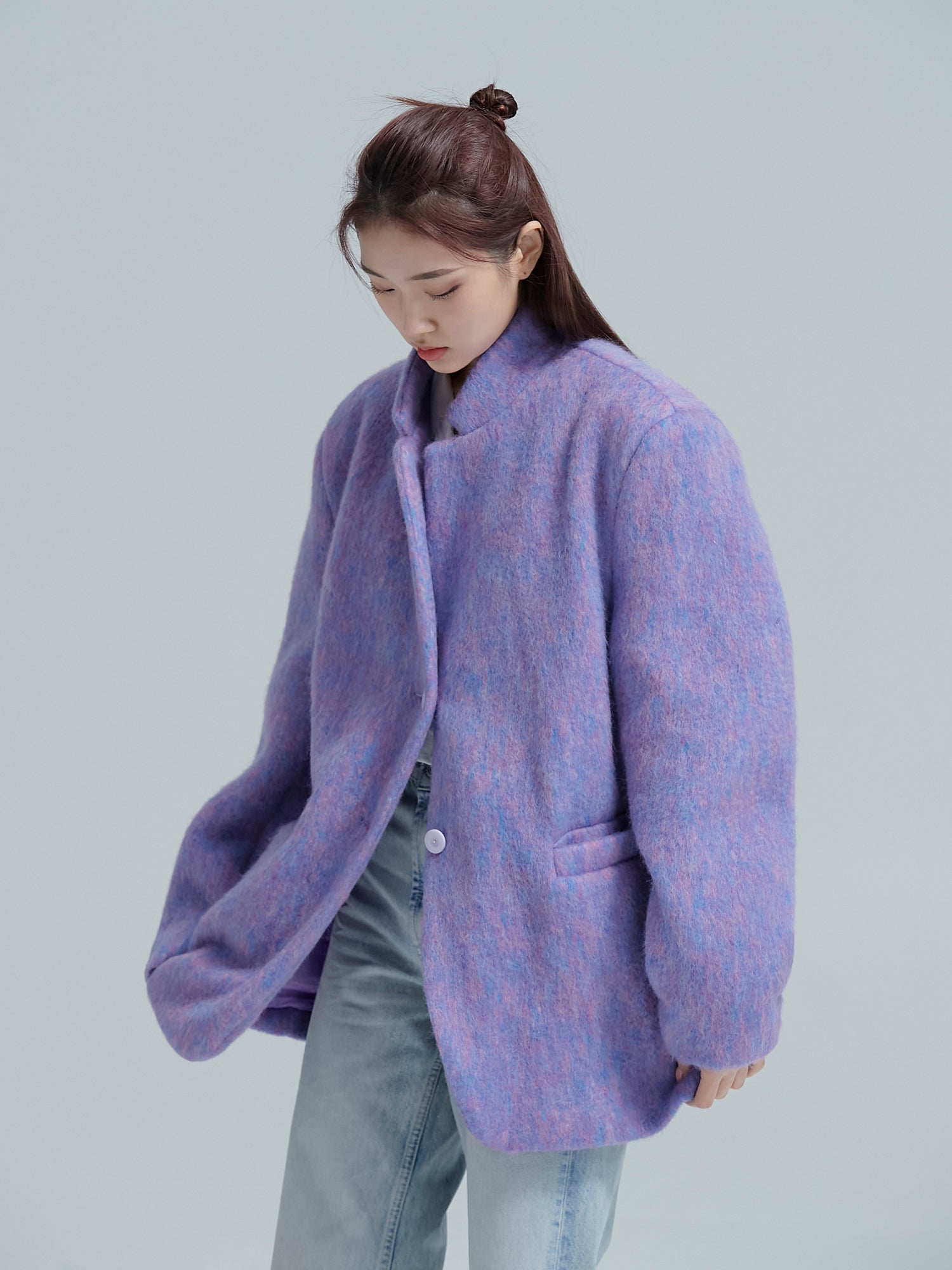 Model is tilted to the side wearing the purple cocoon jacket to show its fabric and button details.