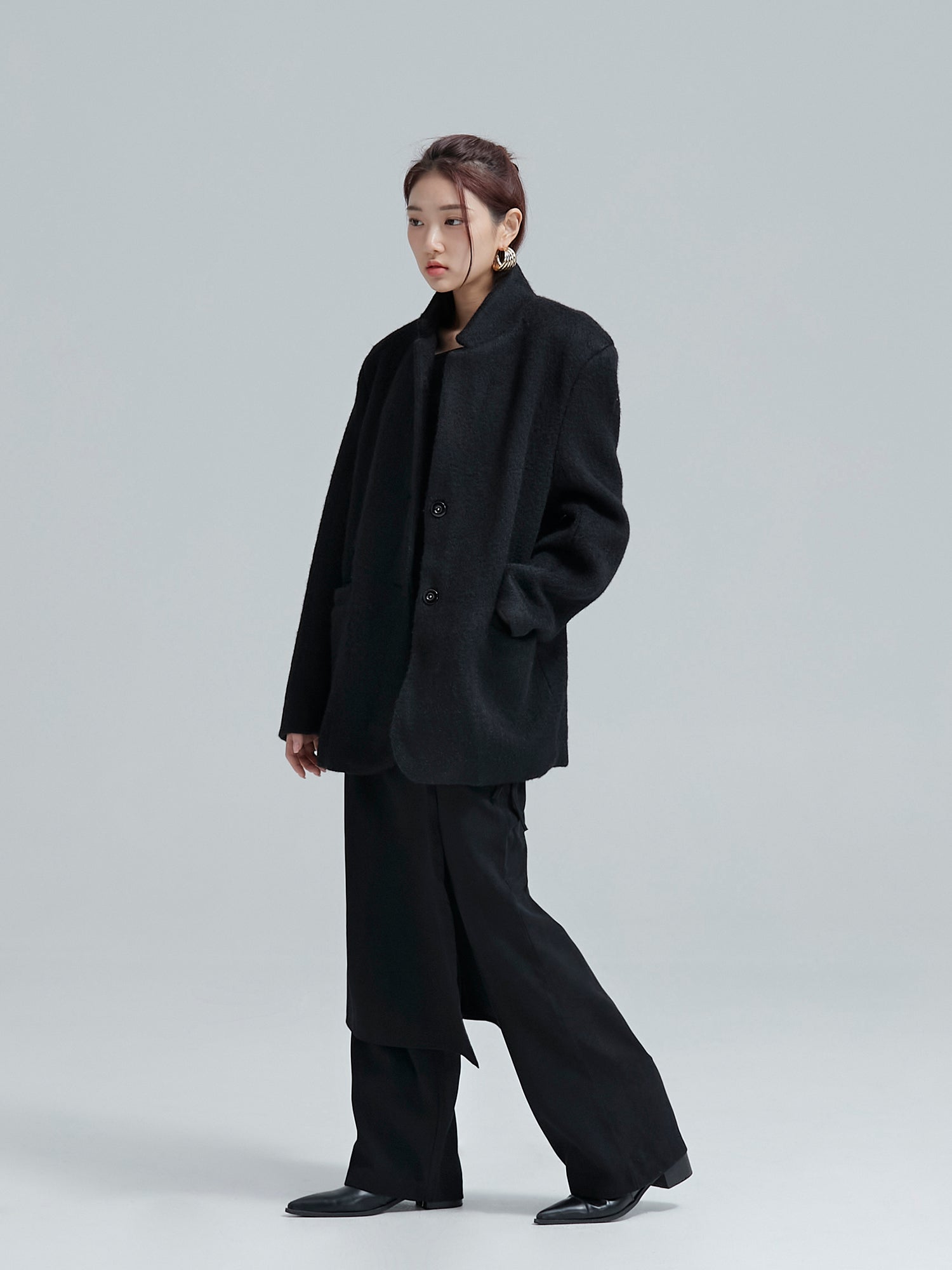 The model, casting a sidelong glance, showcases the black cocoon jacket, embodying the stylish flair of Korean street fashion.