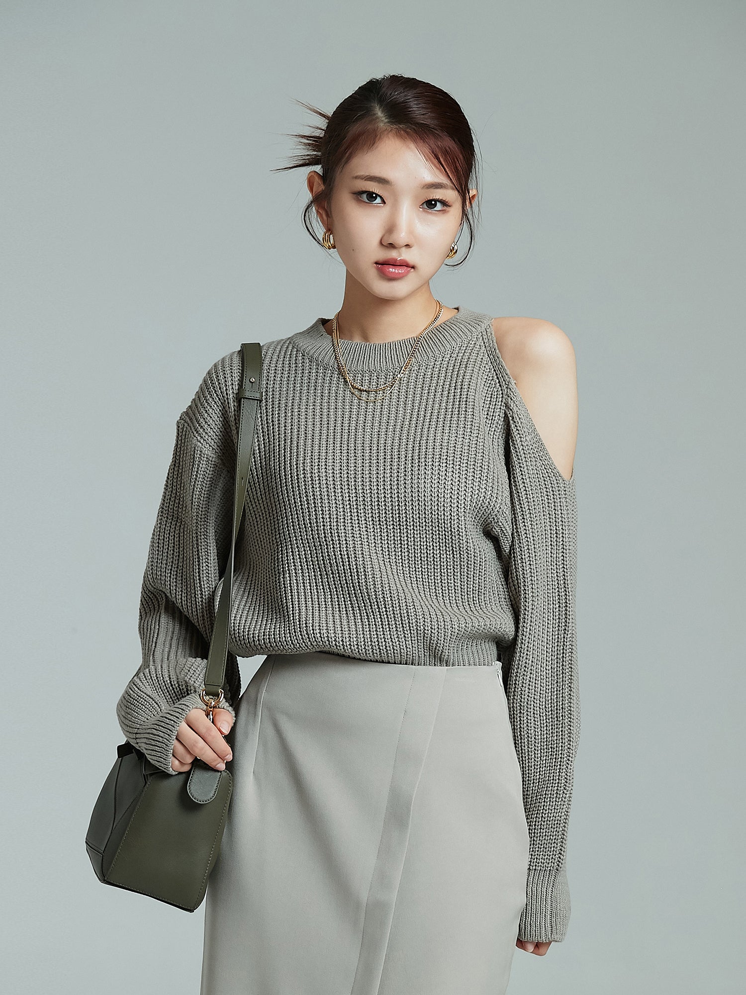 Front view of the model wearing the cold shoulder sweater tucked inside the skirt.