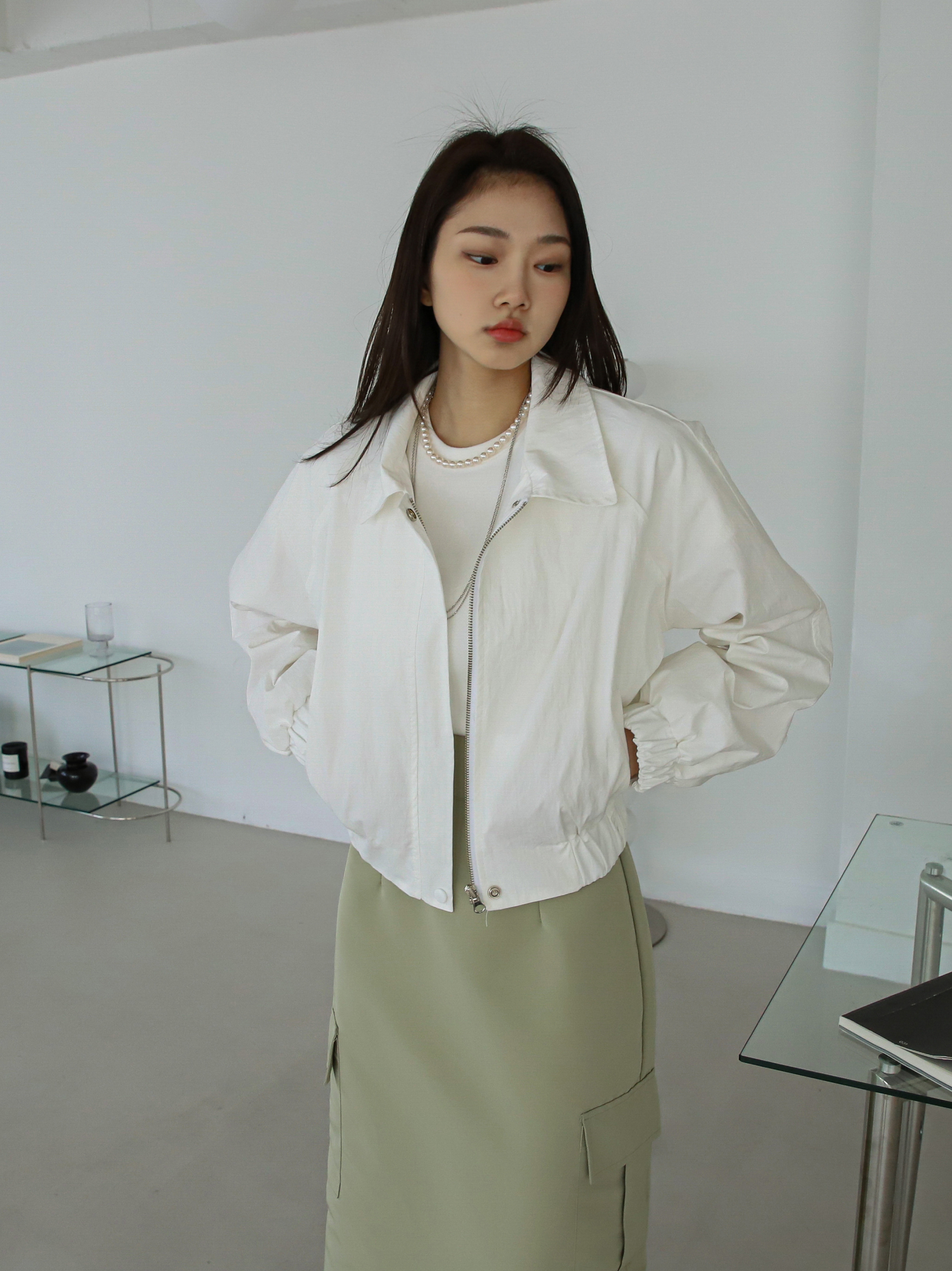 A slightly angled view of a model wearing a collared bomber jacket.