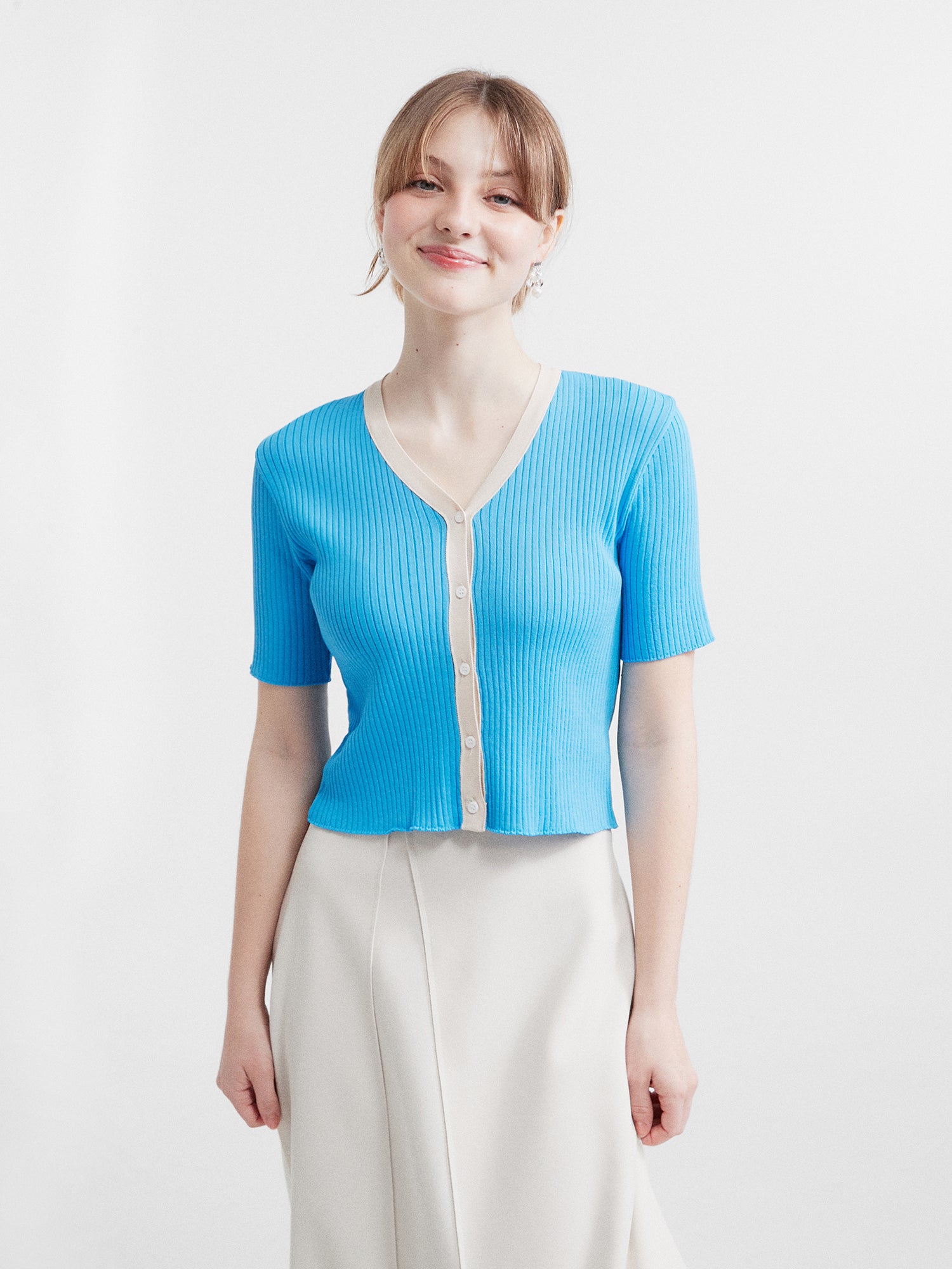 Front view of the model showcasing Korean aesthetic outfits with impeccable style, as she effortlessly pairs a blue contrasting trim cardigan with an elegant ivory tulip wrap skirt, creating a harmonious and fashionable ensemble.