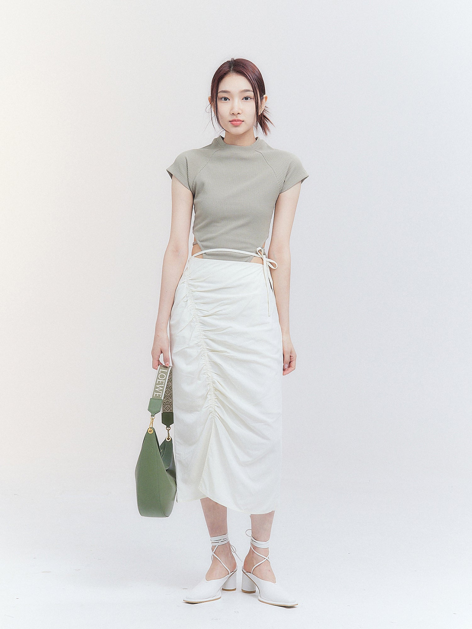 A full-shot of the model wearing the Korean street fashion-inspired Crop Top with Strap, perfectly matched with a drawstring skirt, creating a trendy and fashionable ensemble.