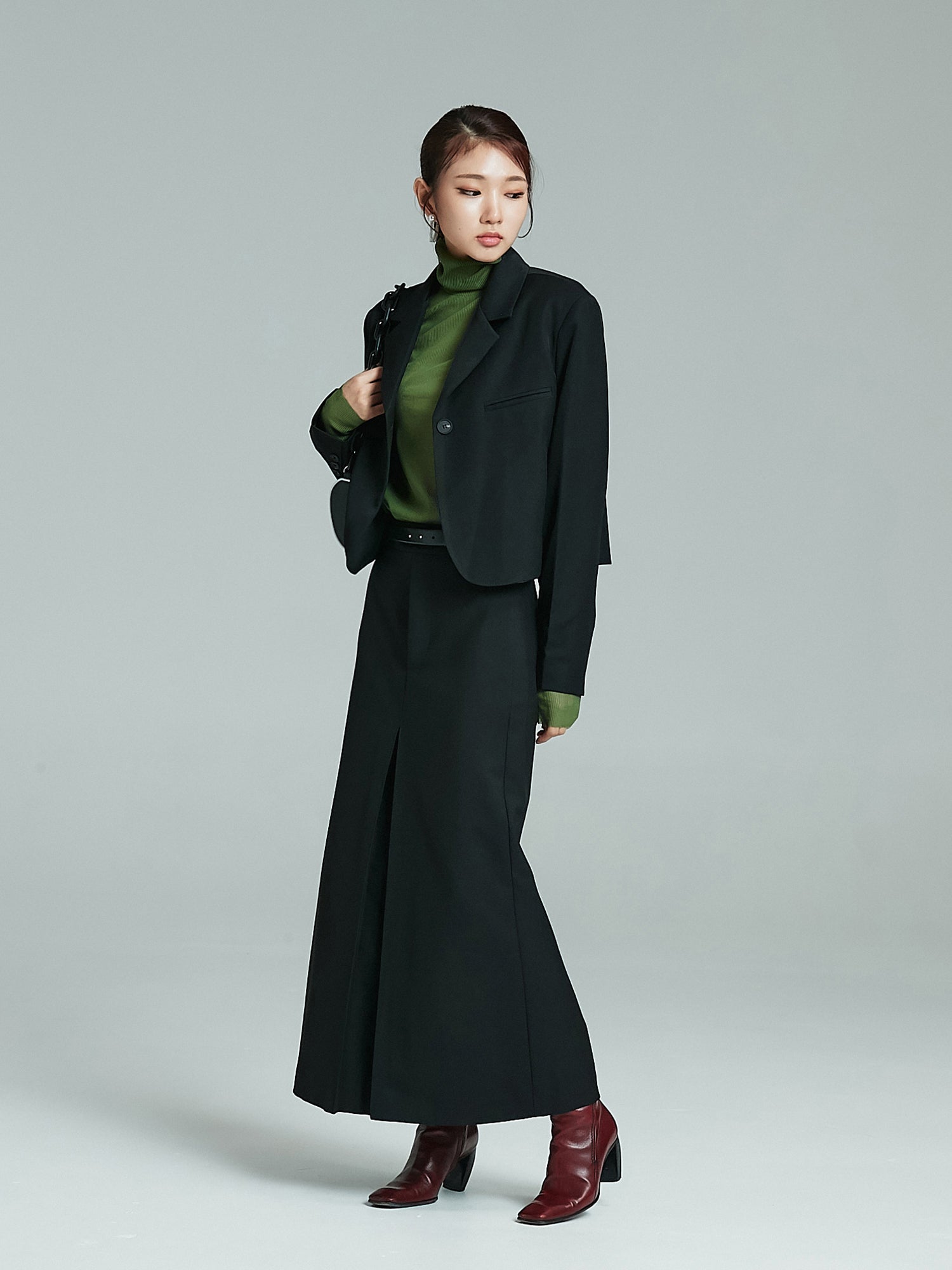 A tilted angle of the full-shot of the model wearing the cropped blazer matching it with the maxi skirt.