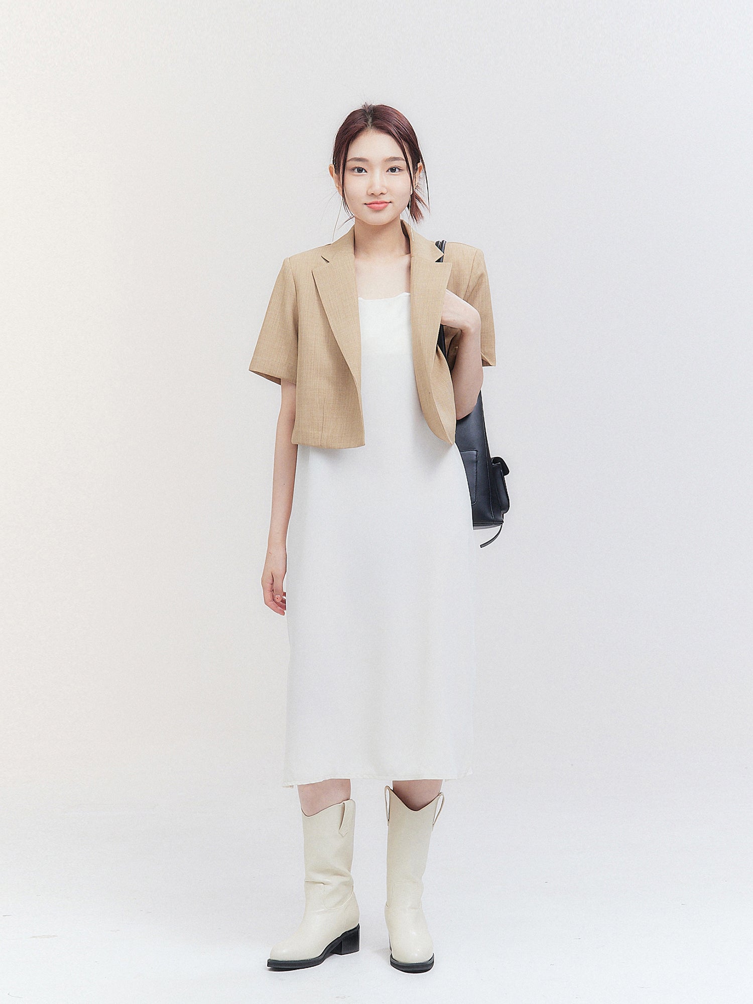 A full-length of the model wearing the cropped blazer matched it with white midi dress.