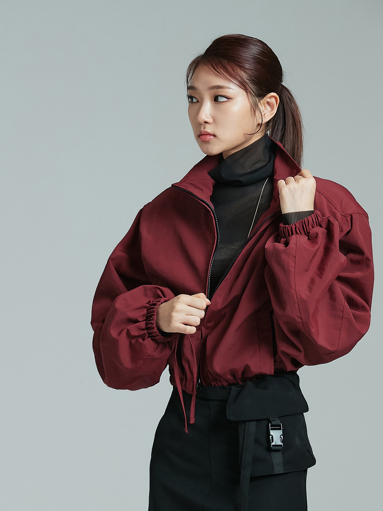 The front view of the model, exuding Korean street fashion vibes, as she stylishly unzips the cropped bomber jacket.