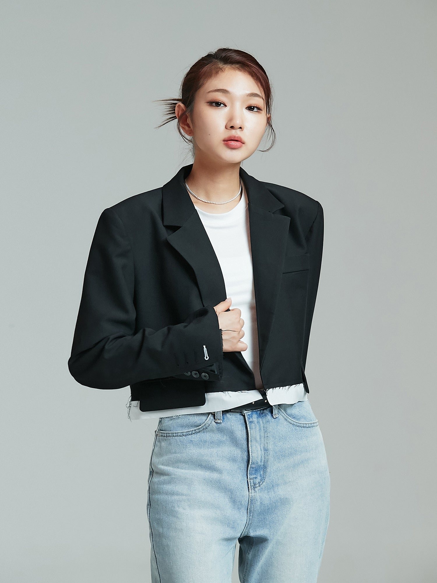 A tilted angle of the model wearing the black cropped layered blazer