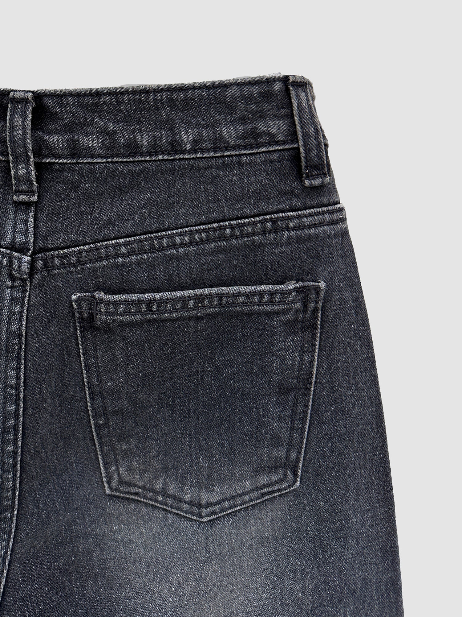 A close-up shot of the back pocket of the dark washed jeans showing the intricate seam stitching and fabric of the jeans.