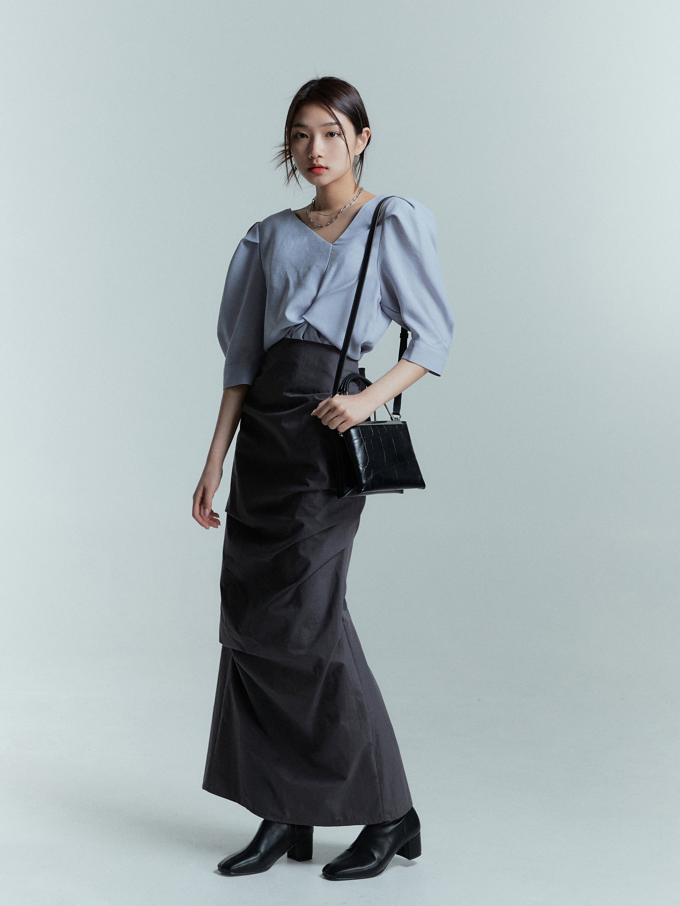 Sideview angle of a model wearing a black draped skirt.