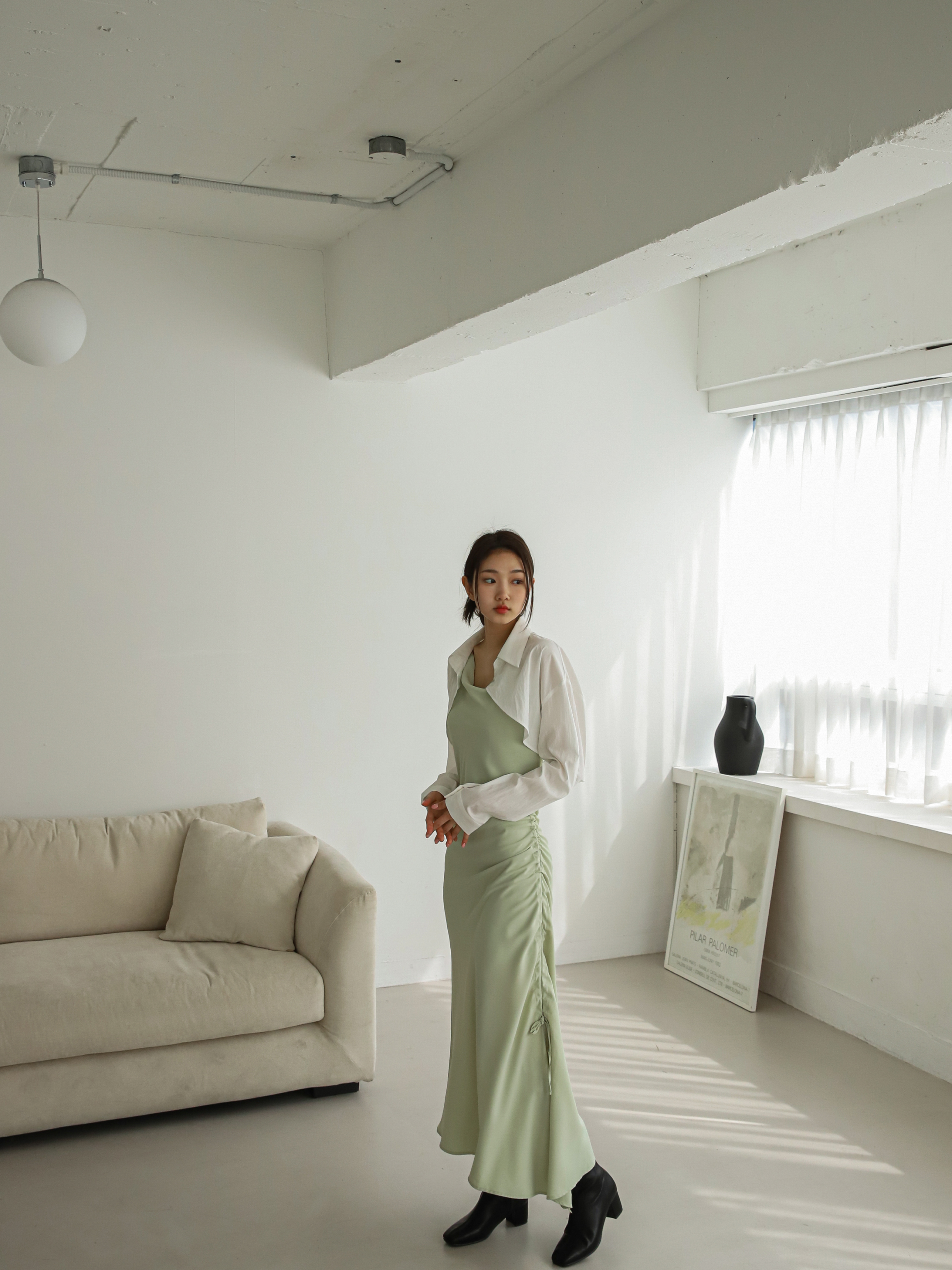 A long shot of a model standing wearing a maxi dress showing the intricacies of the drawstring design.