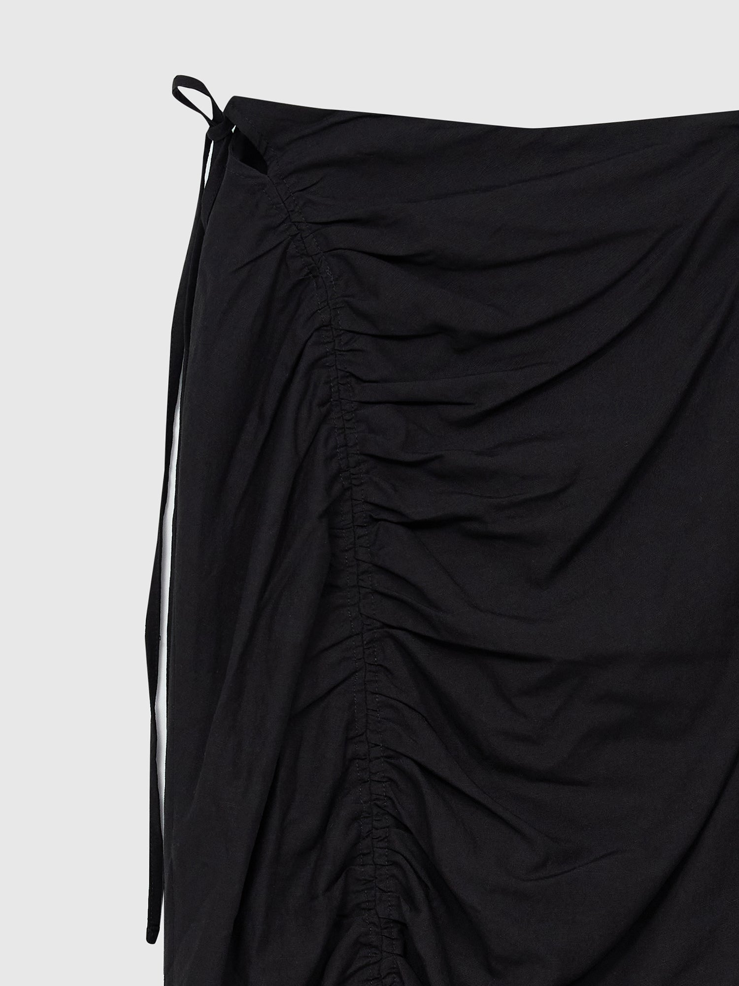 A close-up view of the drawstring skirt showing the side tie knotted ruched detail of the skirt.