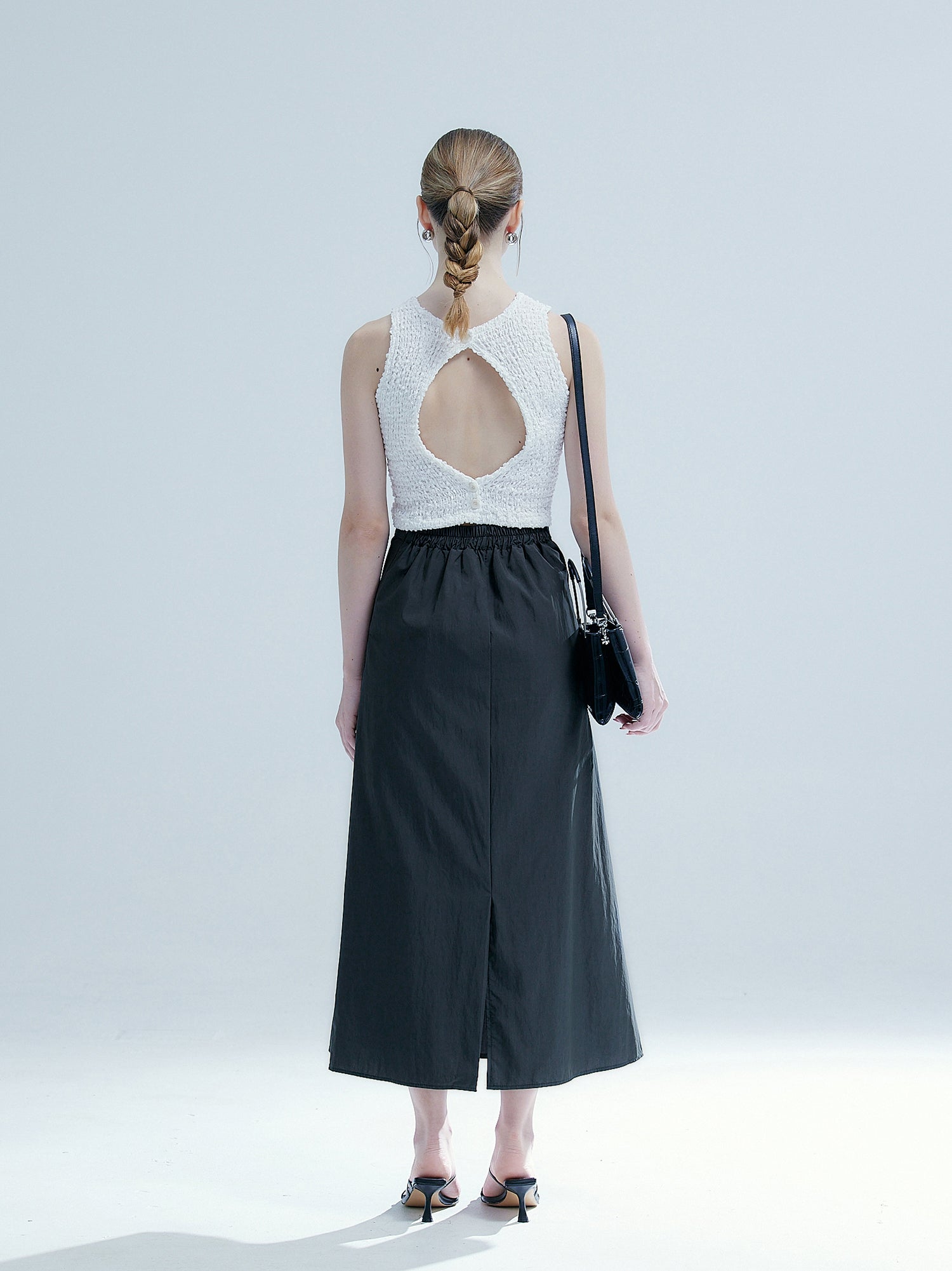 Back view of the model wearing the charcoal elasticated midi skirt showing the back slit detail of the midi skirt.