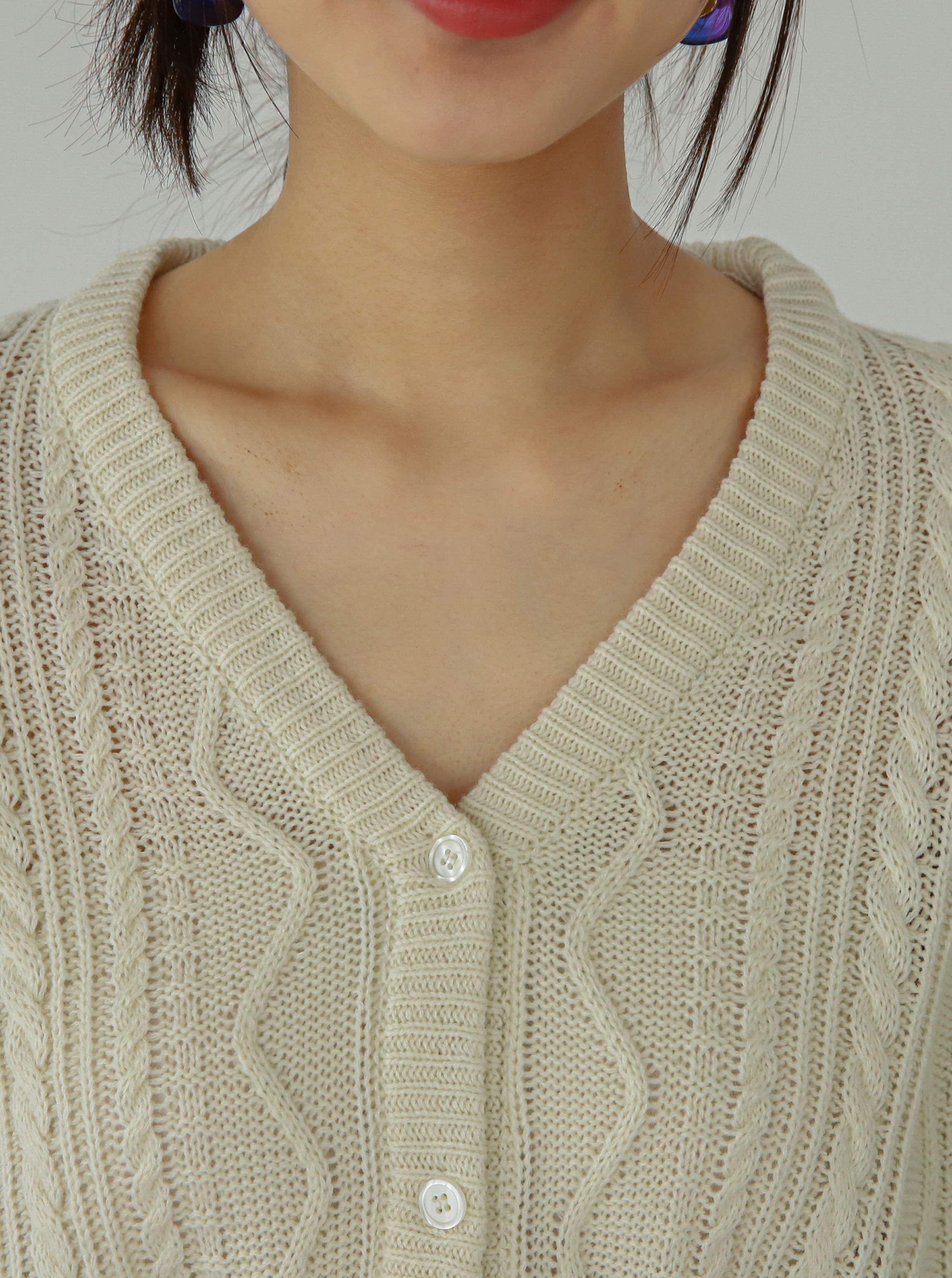 A close-up view of the v-neck and button front details on the embroidered sweater.