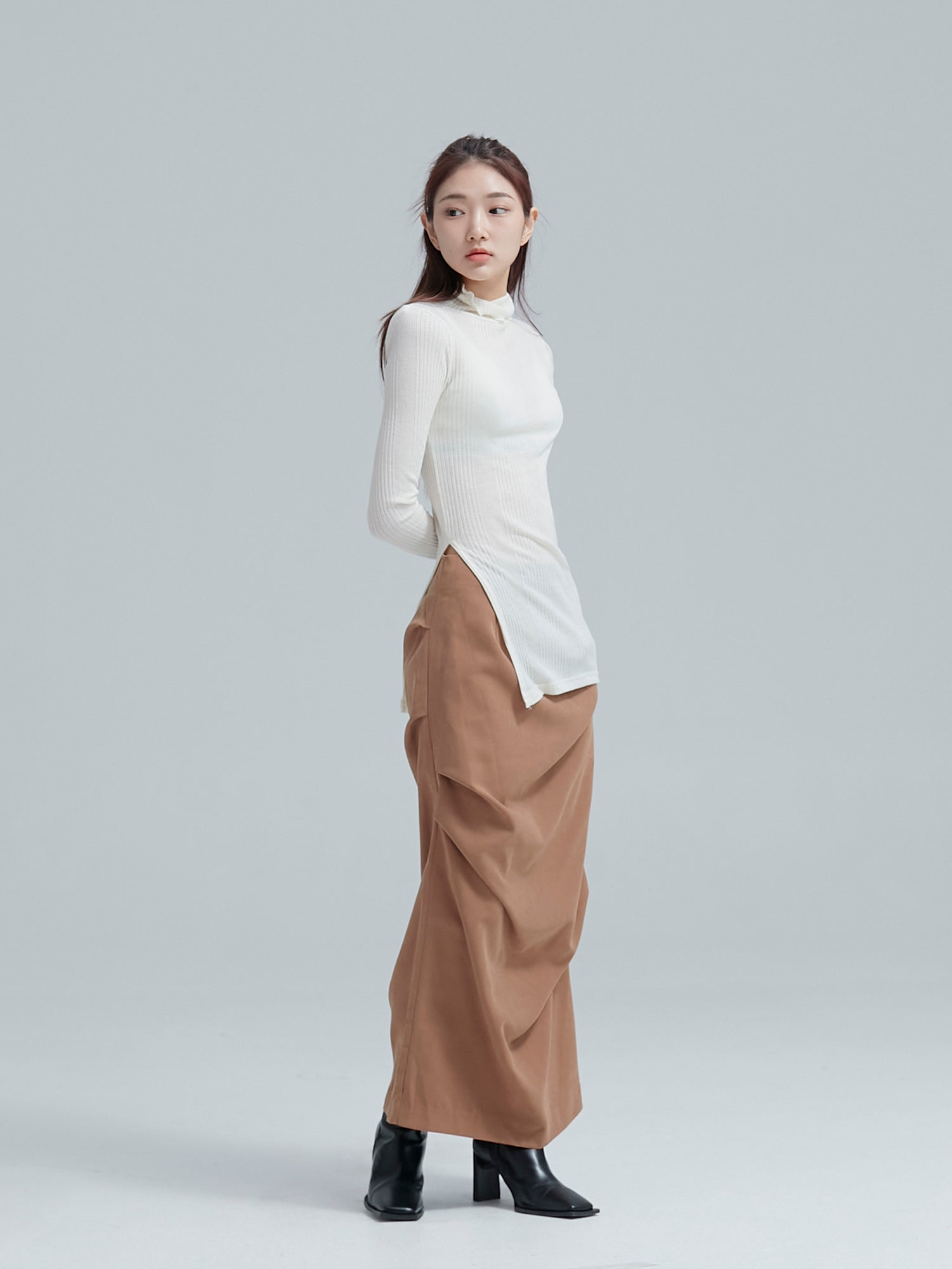 A tilted angle of the model wearing the fall draped skirt accentuating its draped design detail.