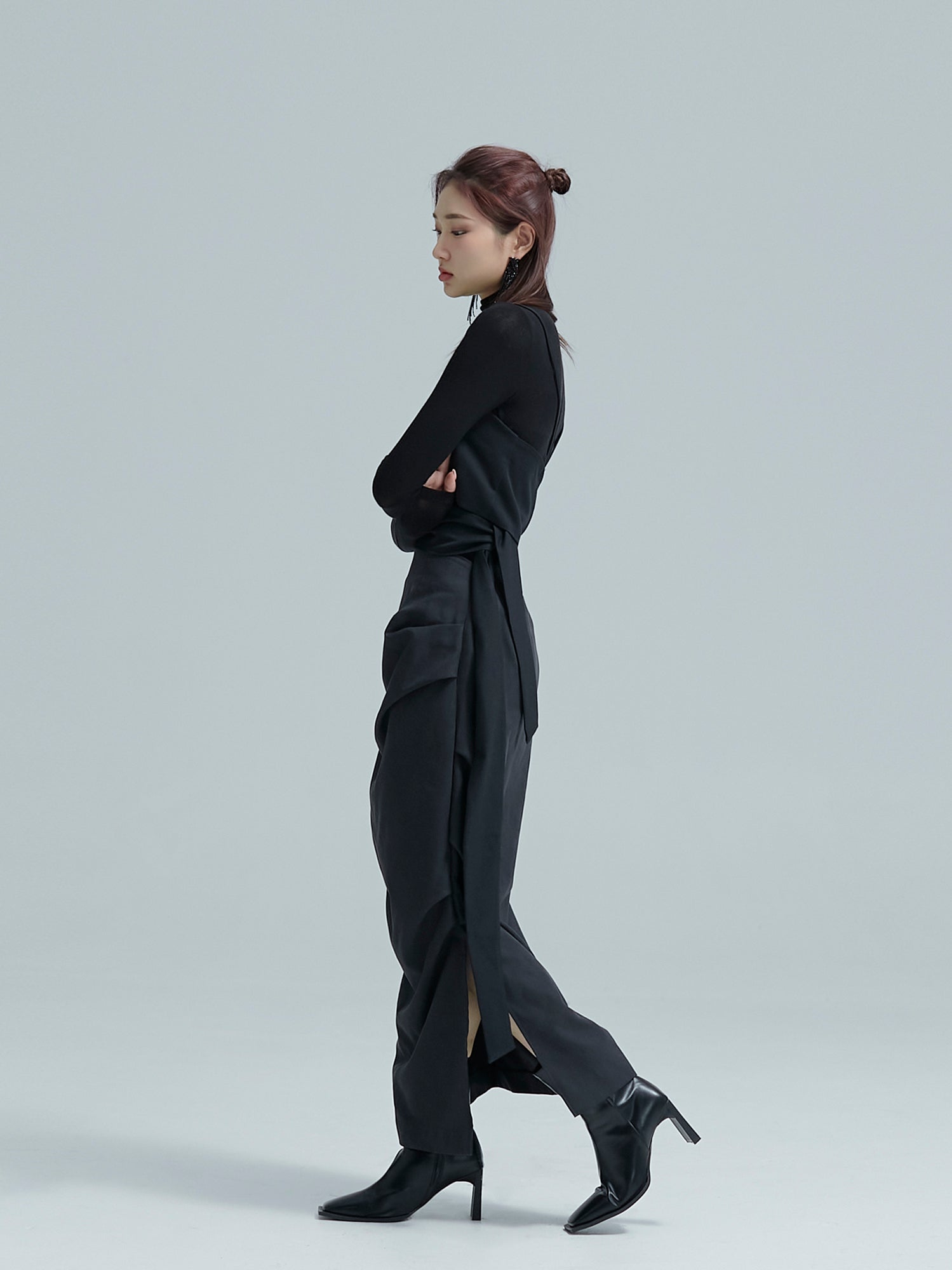 A side angle of the model wearing the black fall draped skirt to showcase its side draped detailed design of the skirt.