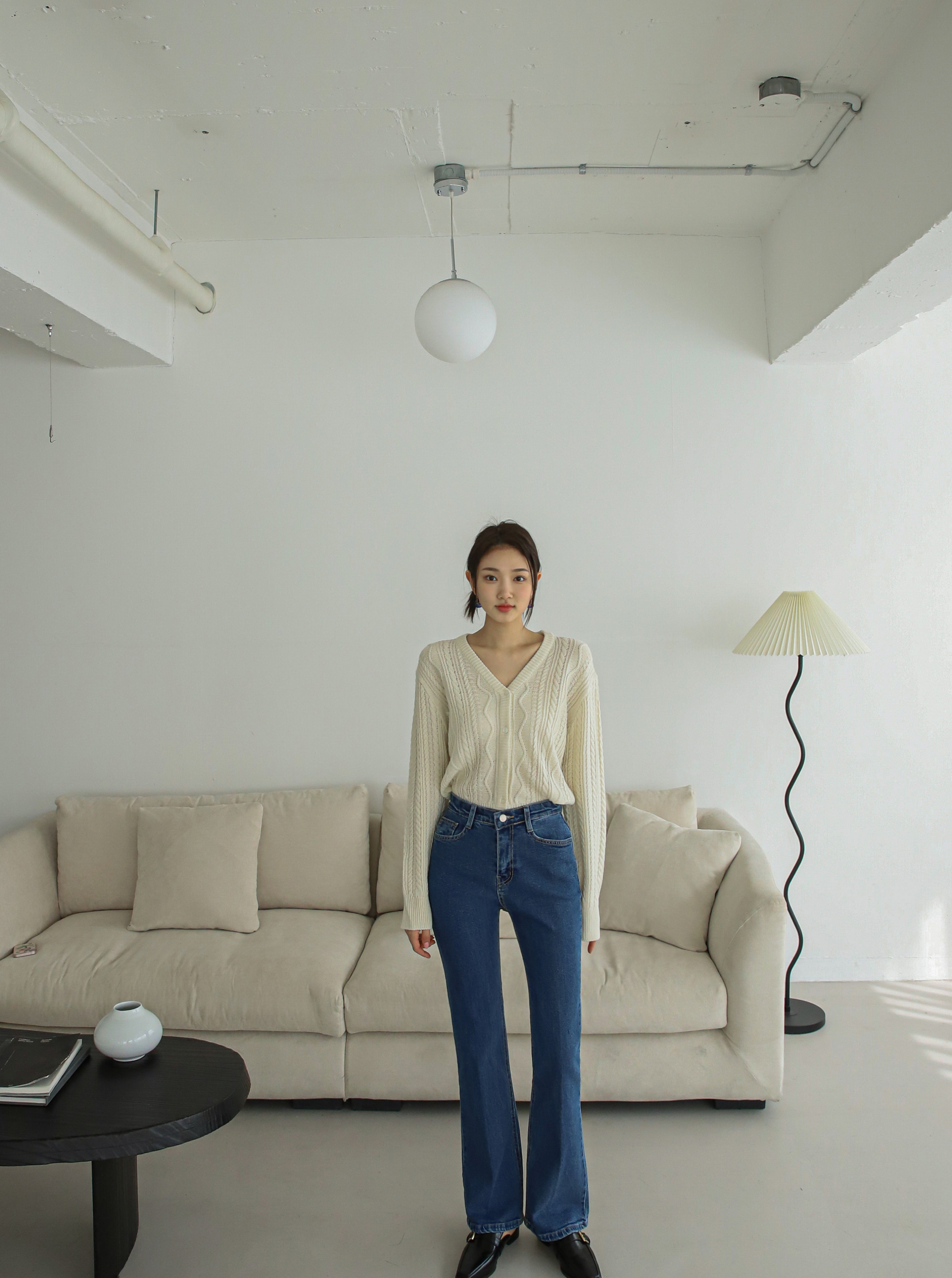 A long shot of a model standing wearing a dark flare jeans matching it with the embroidered sweater.