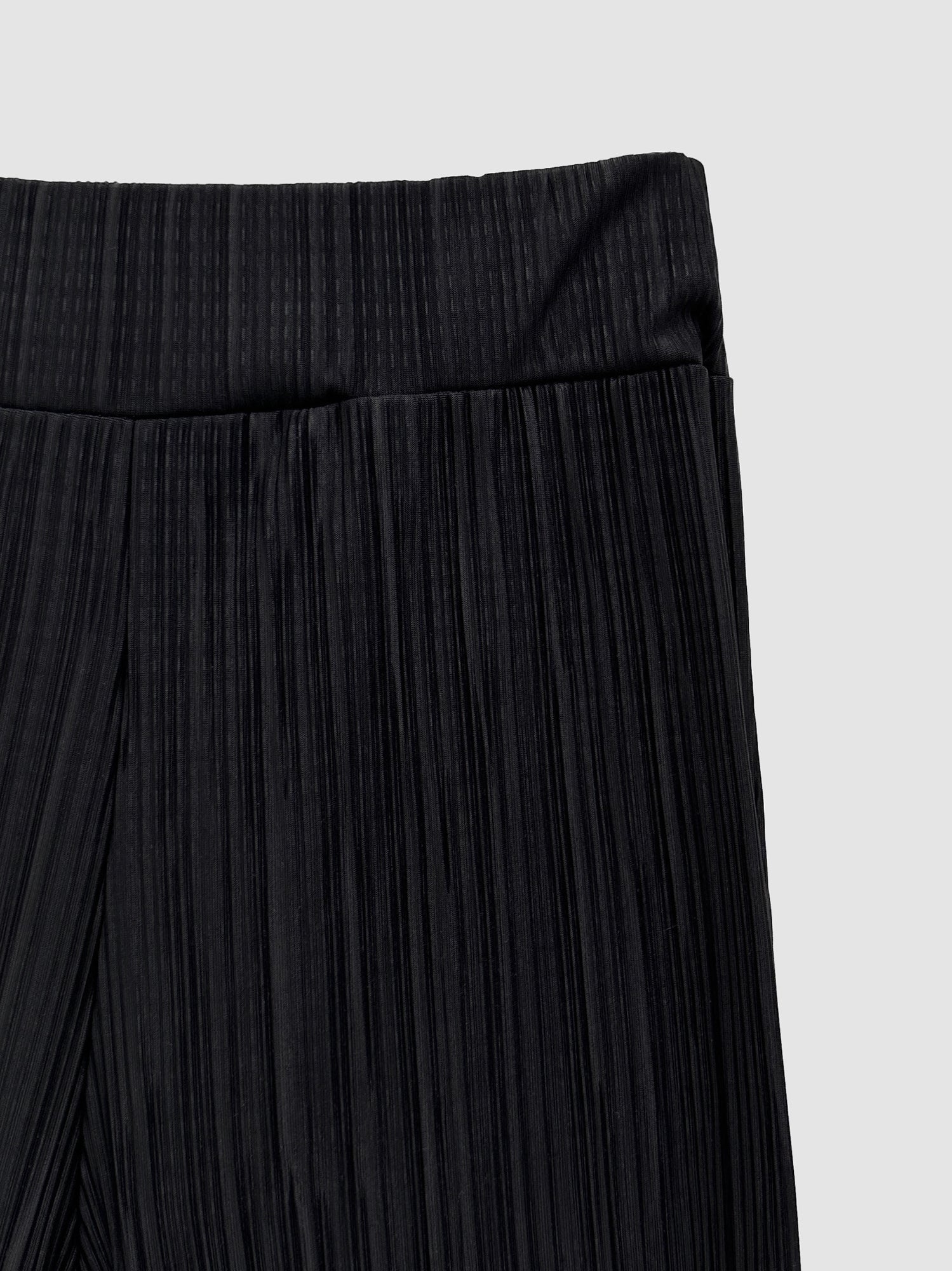 A close-up view of the black flare pleated pants, capturing the intricate texture of the fabric.