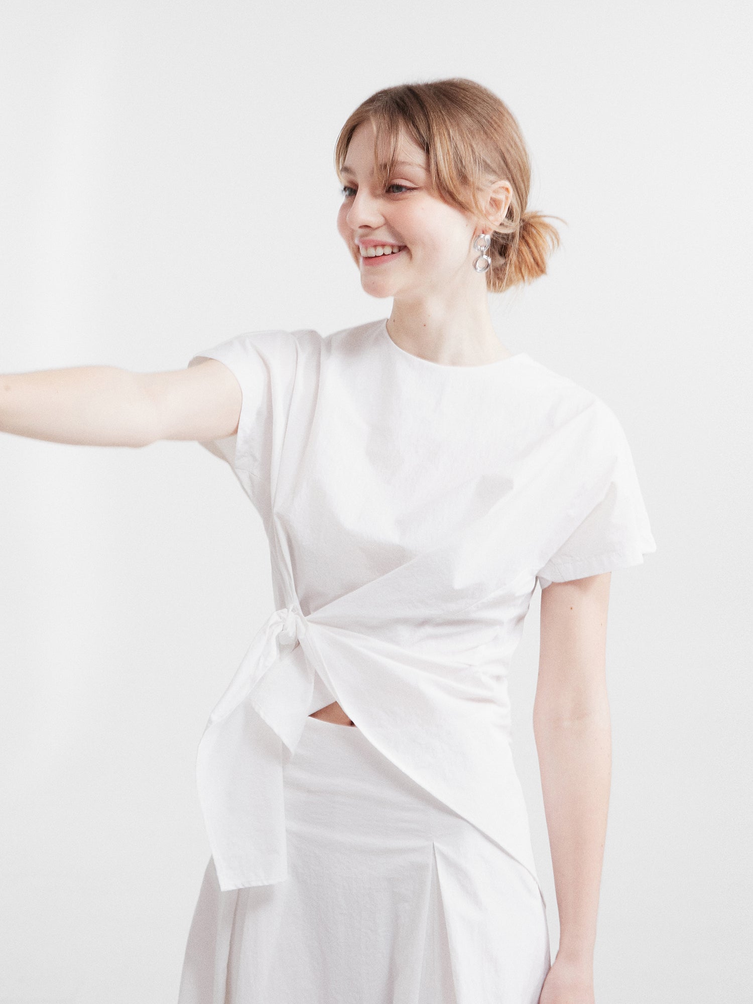 A tilted angle of the front wrap blouse showcasing the wrapping detail of the ivory blouse.