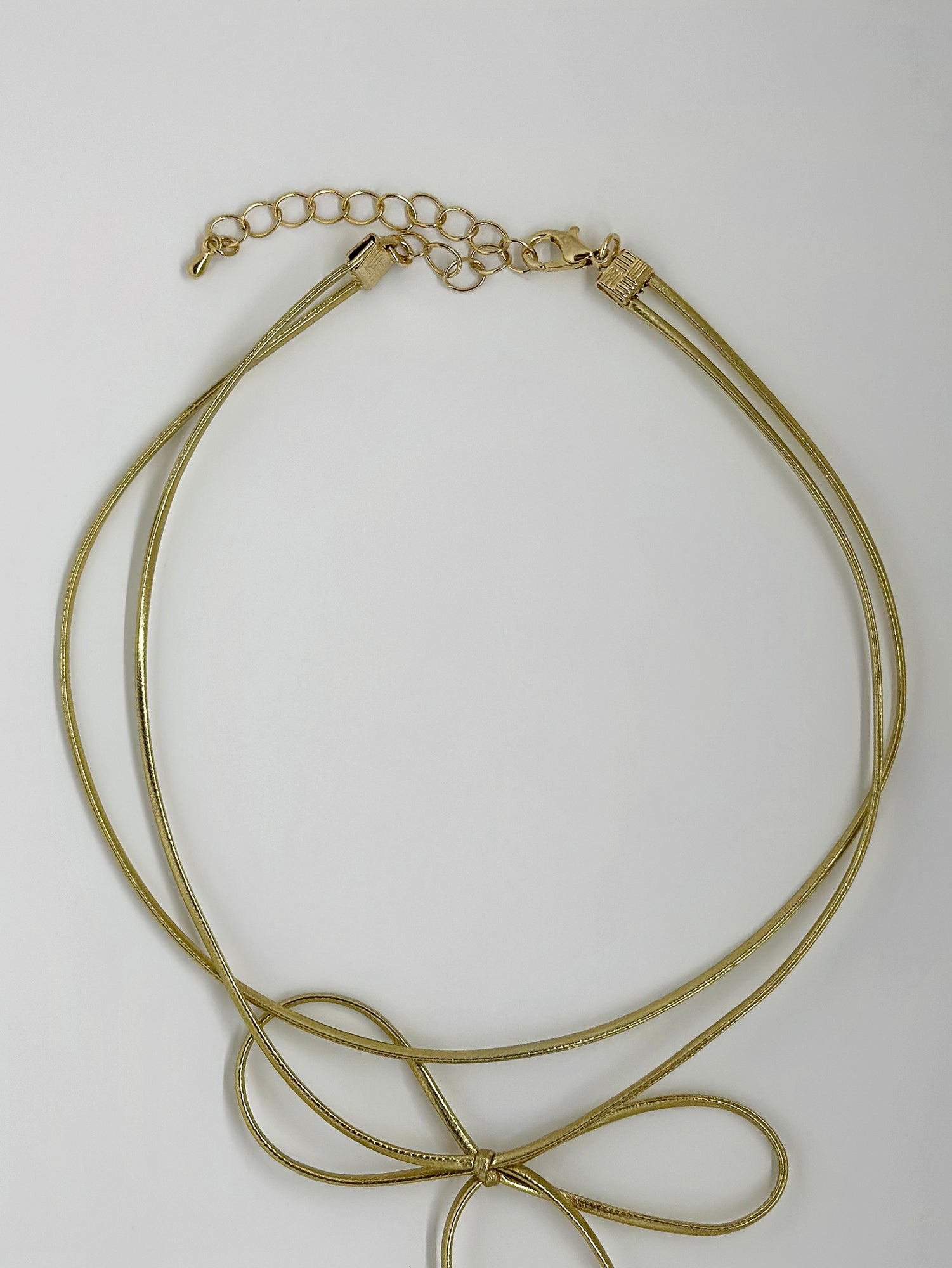 An image of gold knot necklace highlighting the clasps and string design details.