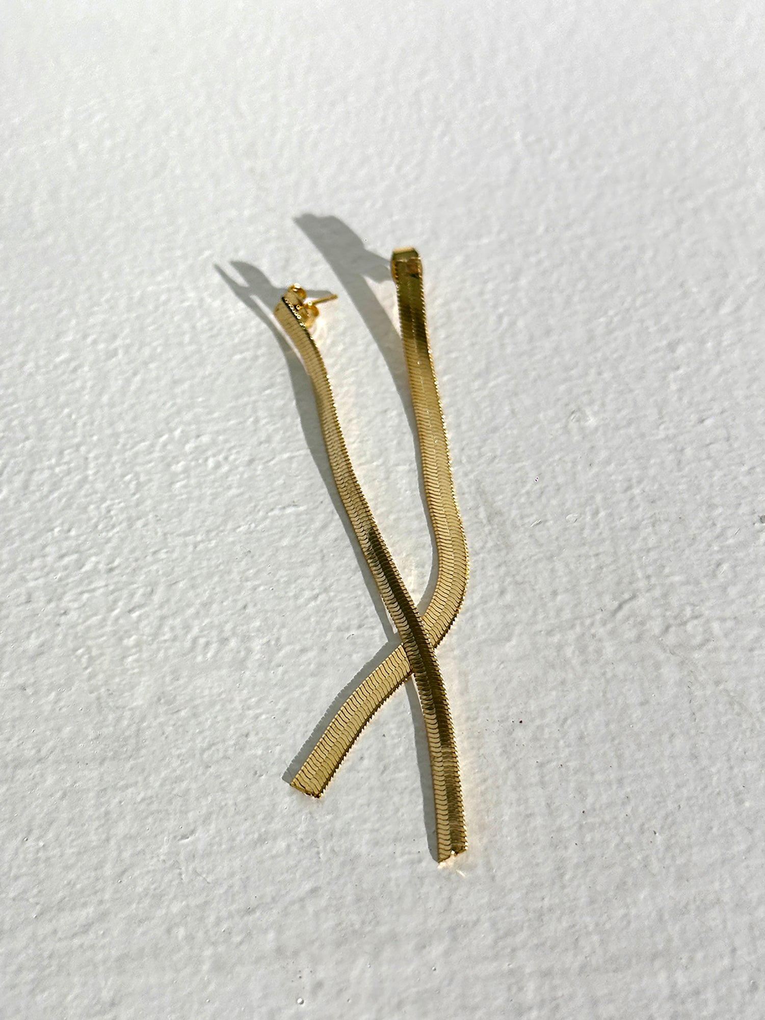 A detailed image of the gold stick dangle earrings displaying the Korean street fashion designs incorporated in the earrings.