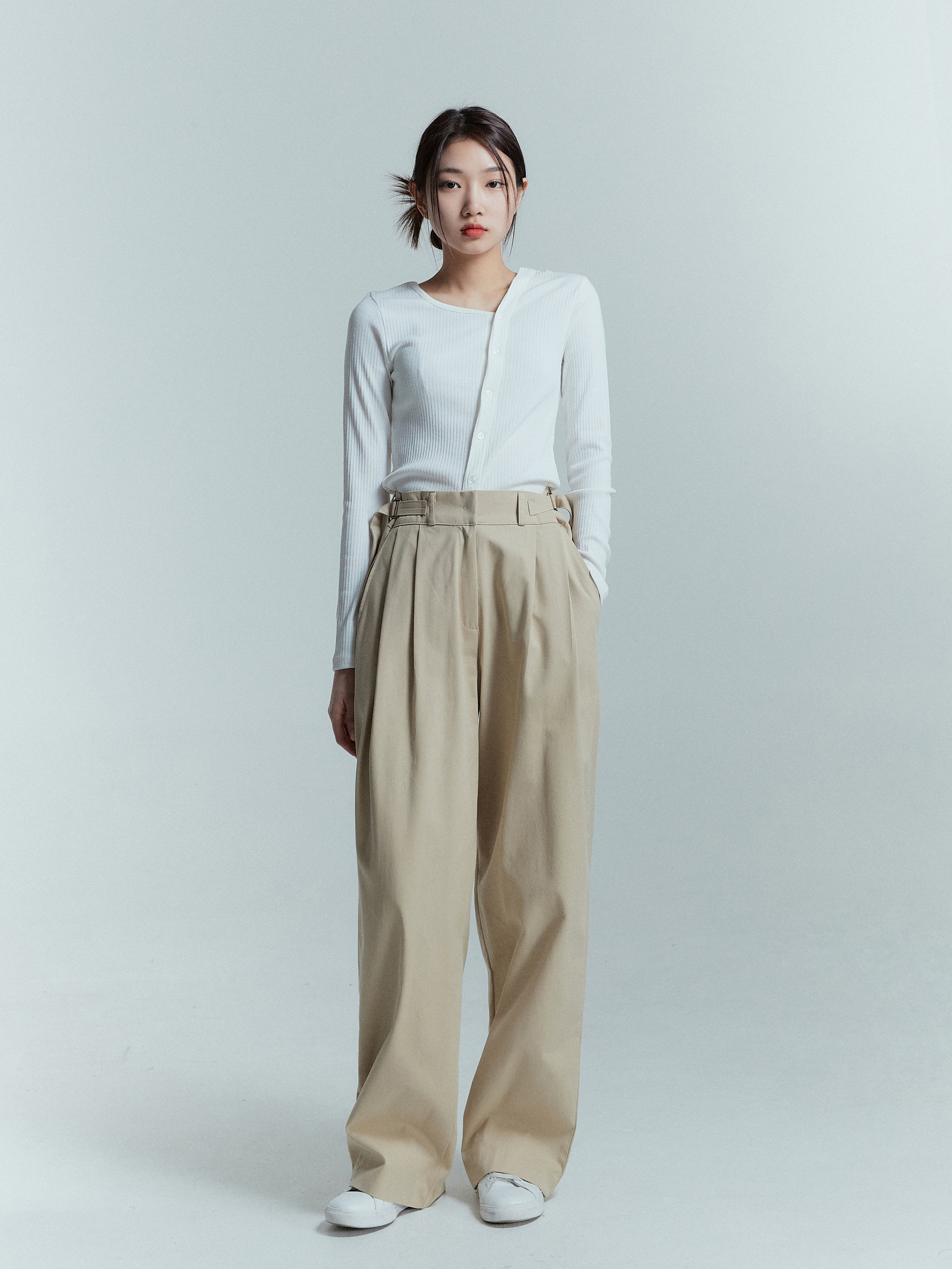 Standing pose of a model wearing a high-rise pleated trouser.