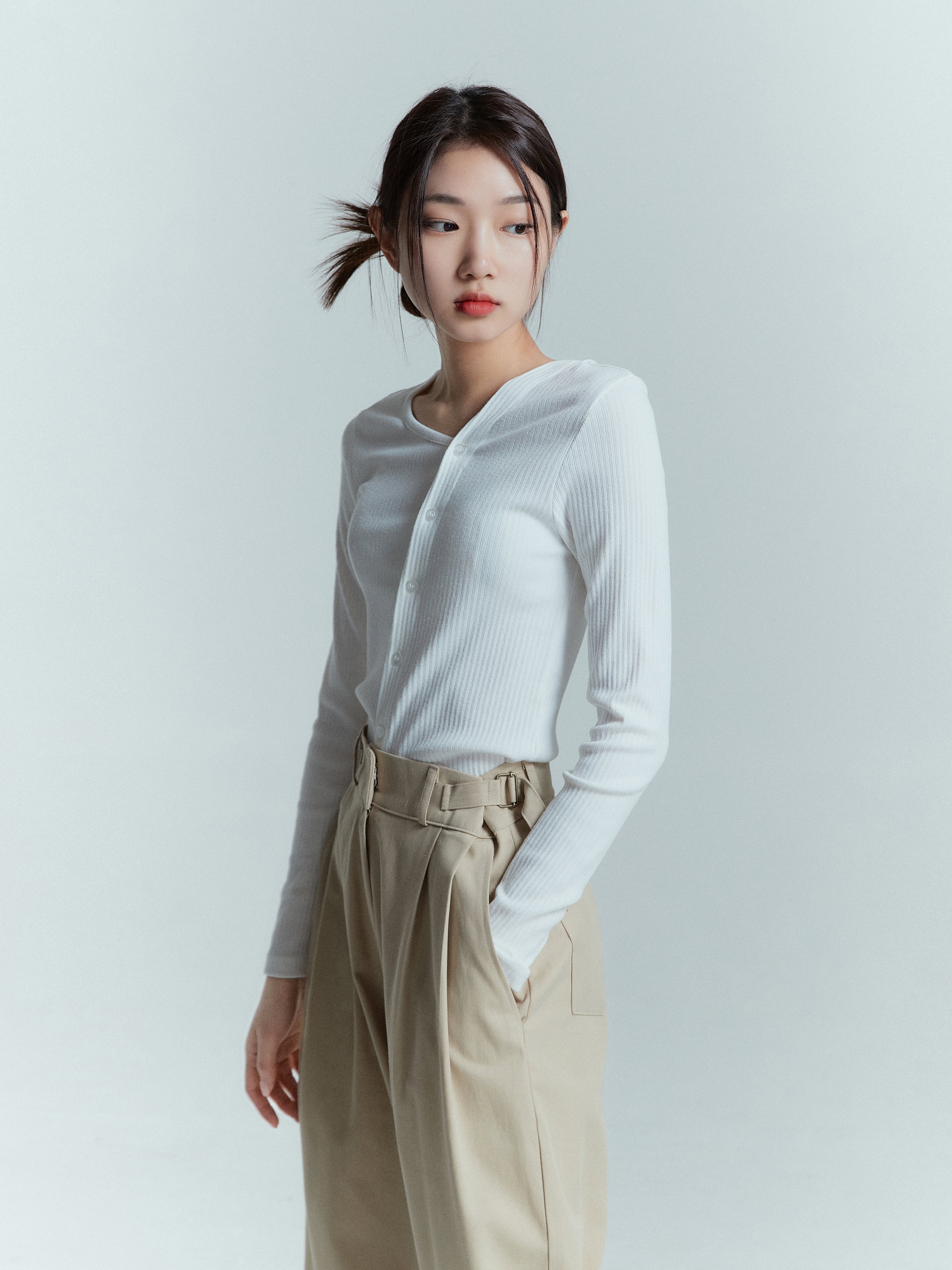 A close-up shot of a model showcasing the high-rise pleated trouser.