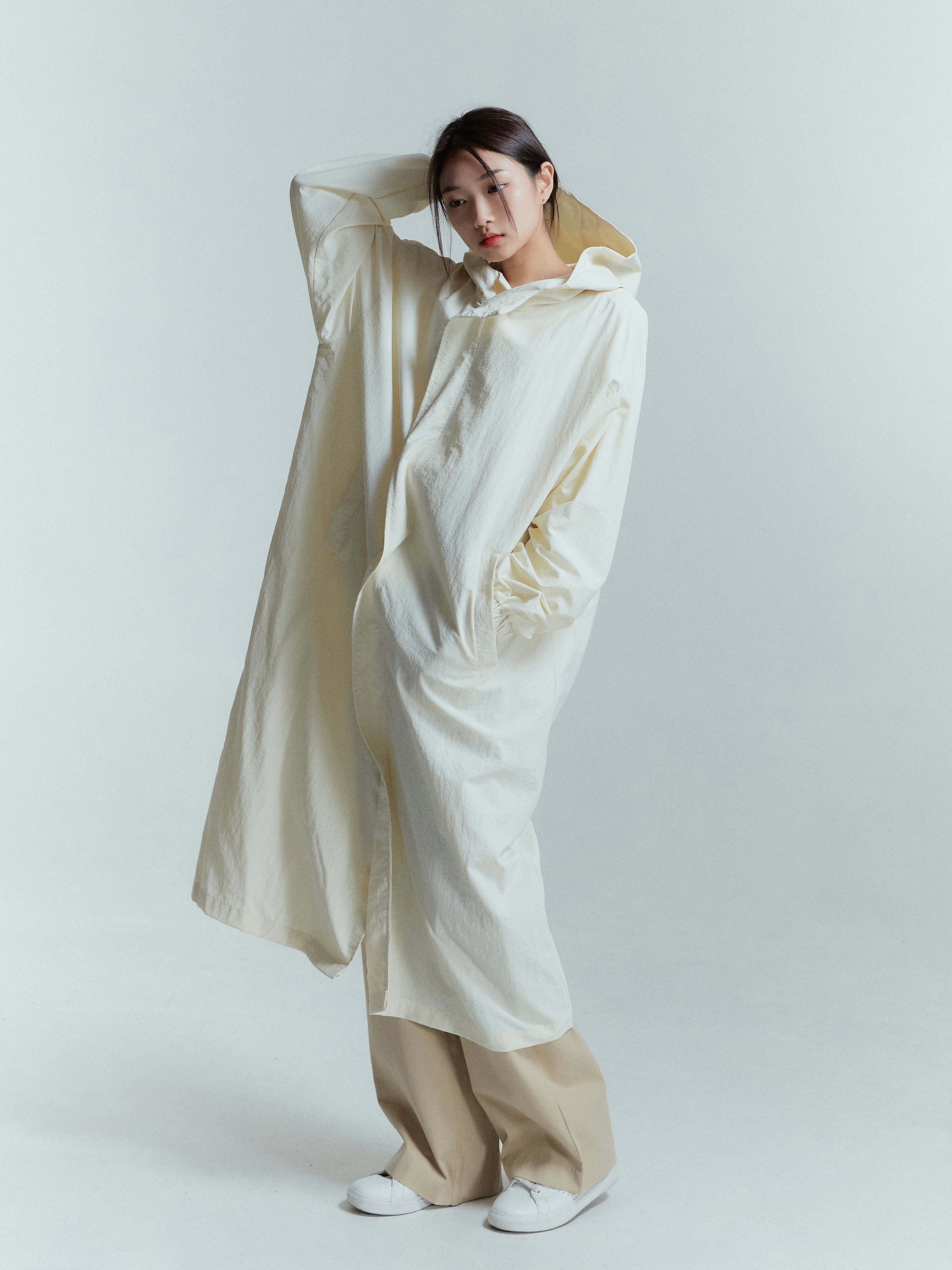 Capture the full-length essence as the model dons the long coat, showcasing its stunning design while trying on the hoodie for a fashionable touch.