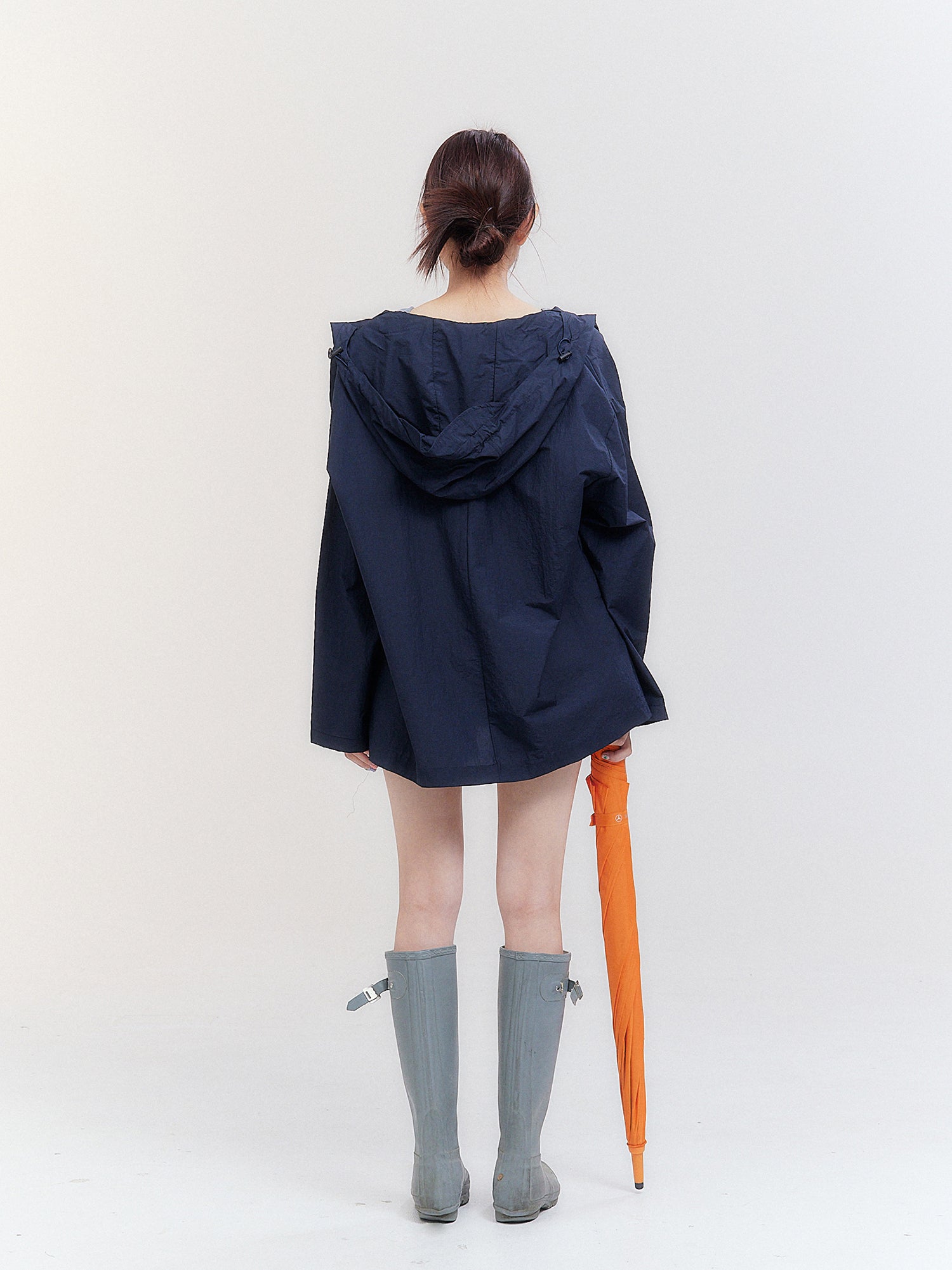 Back view of the model wearing the navy hooded raincoat displaying the back side fitting of the raincoat.