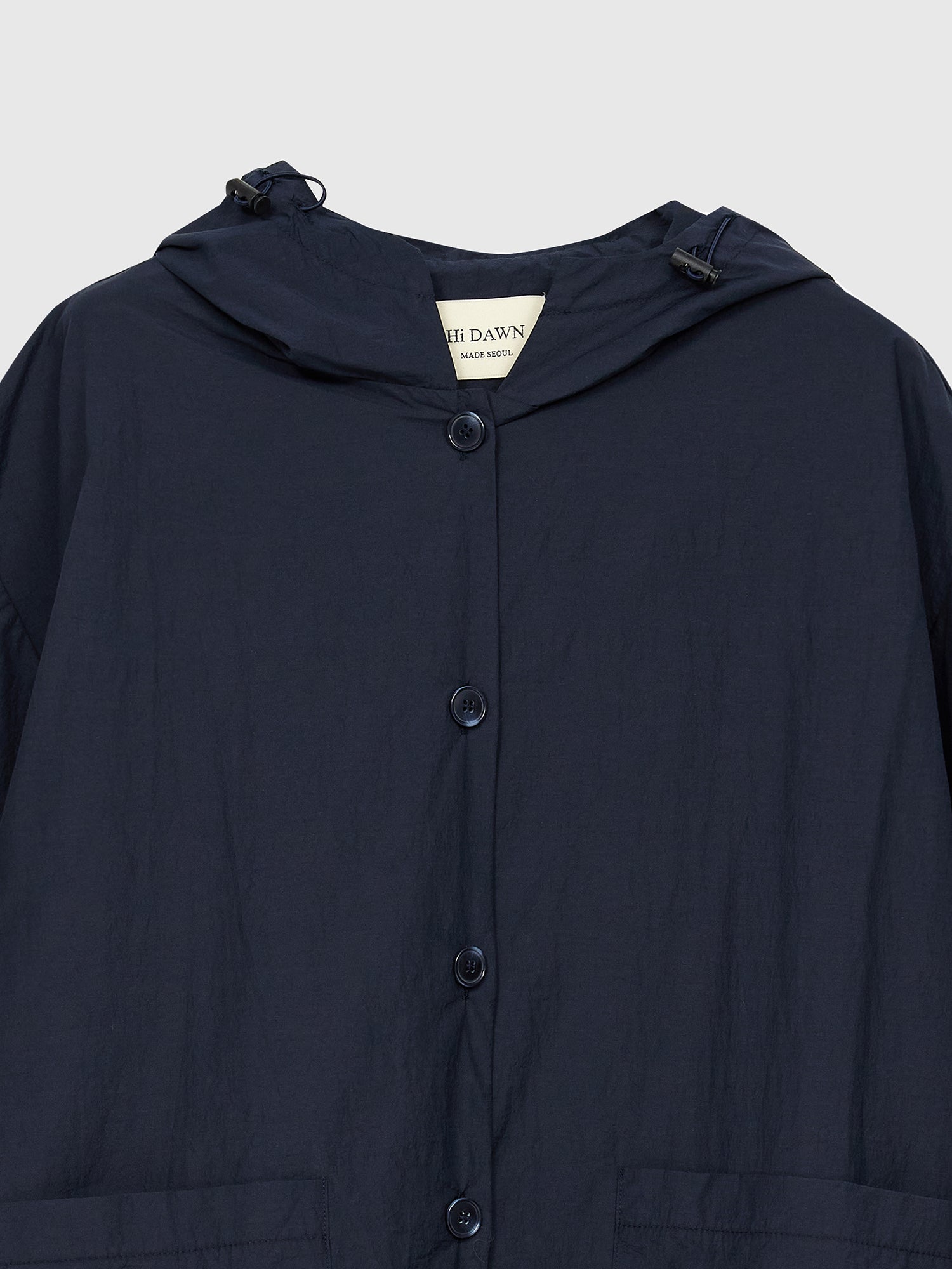 A close-up view of the navy hooded jacket highlighting the buttons and front hooded details.