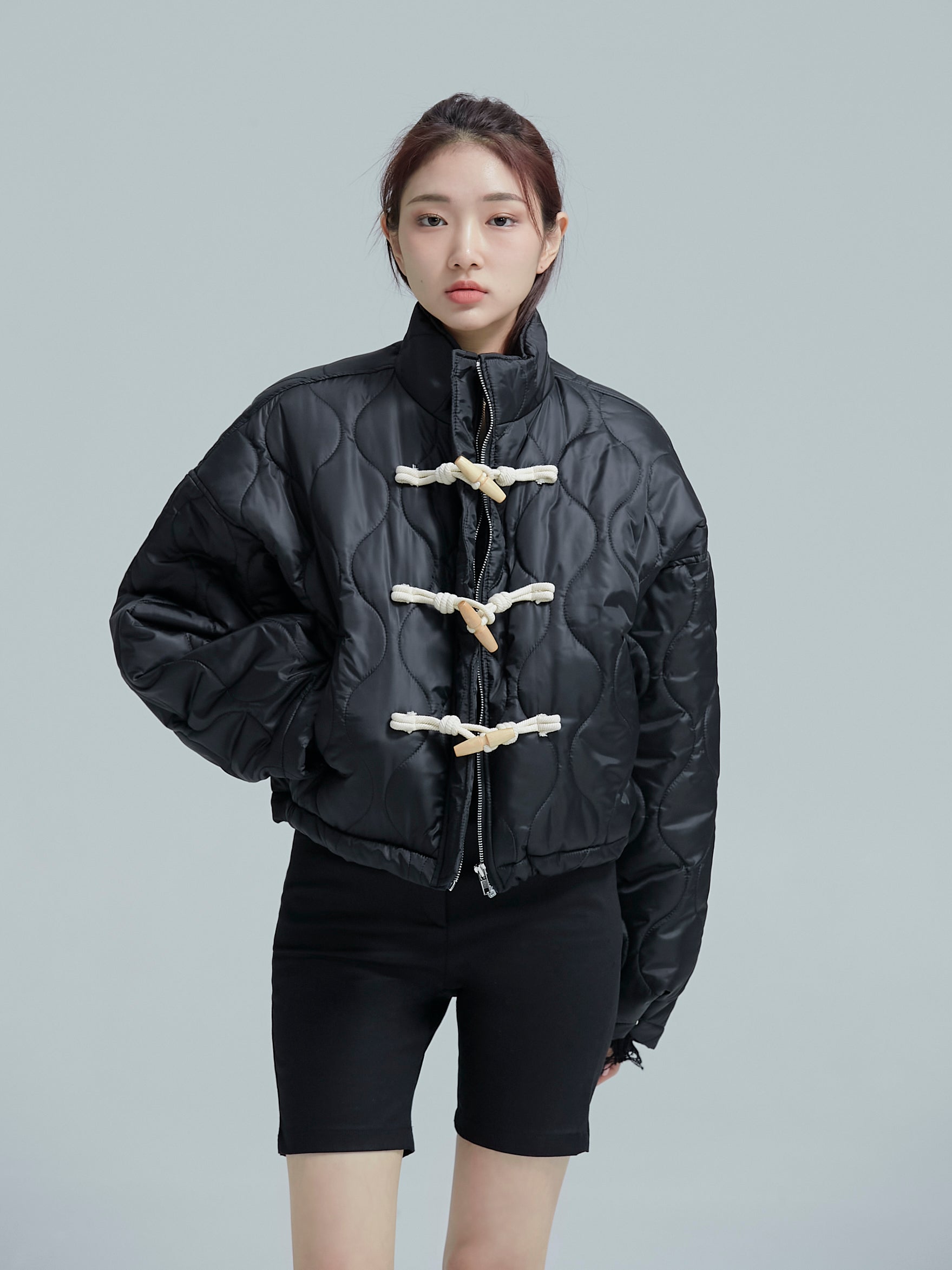 A model is facing front while wearing the black jaguar quilted jacket that has all the buttons closed.