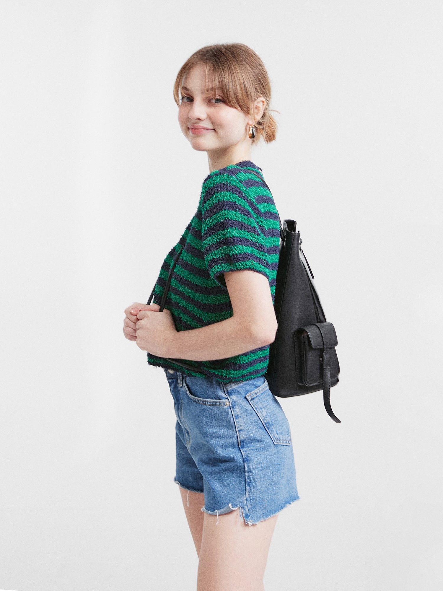 A side view of the model wearing the jean shorts showcasing the low-to-high design of the shorts.