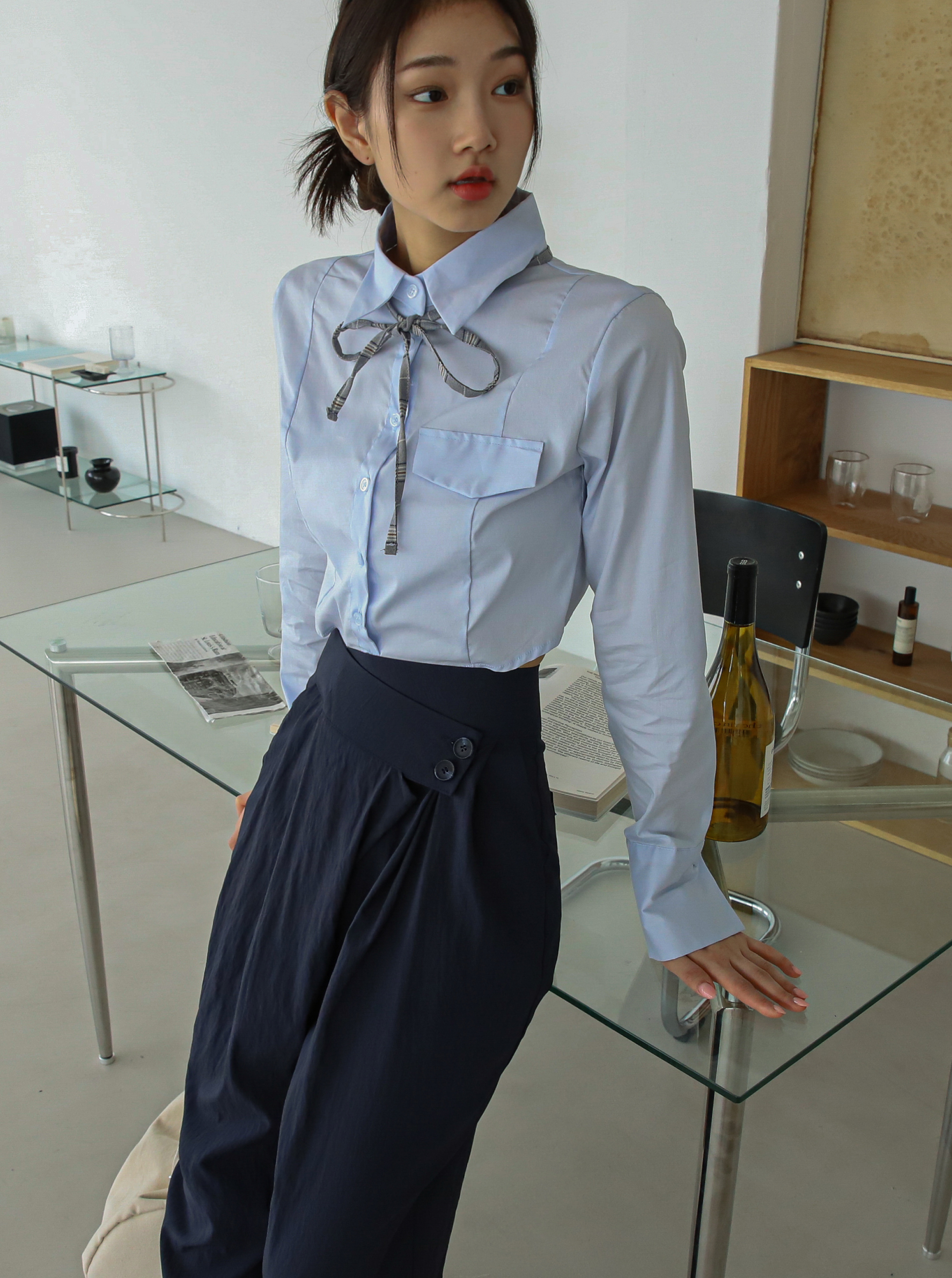 A model striking a pose showing the delicate detail of the laced collar shirt with side-buttoned trouser.