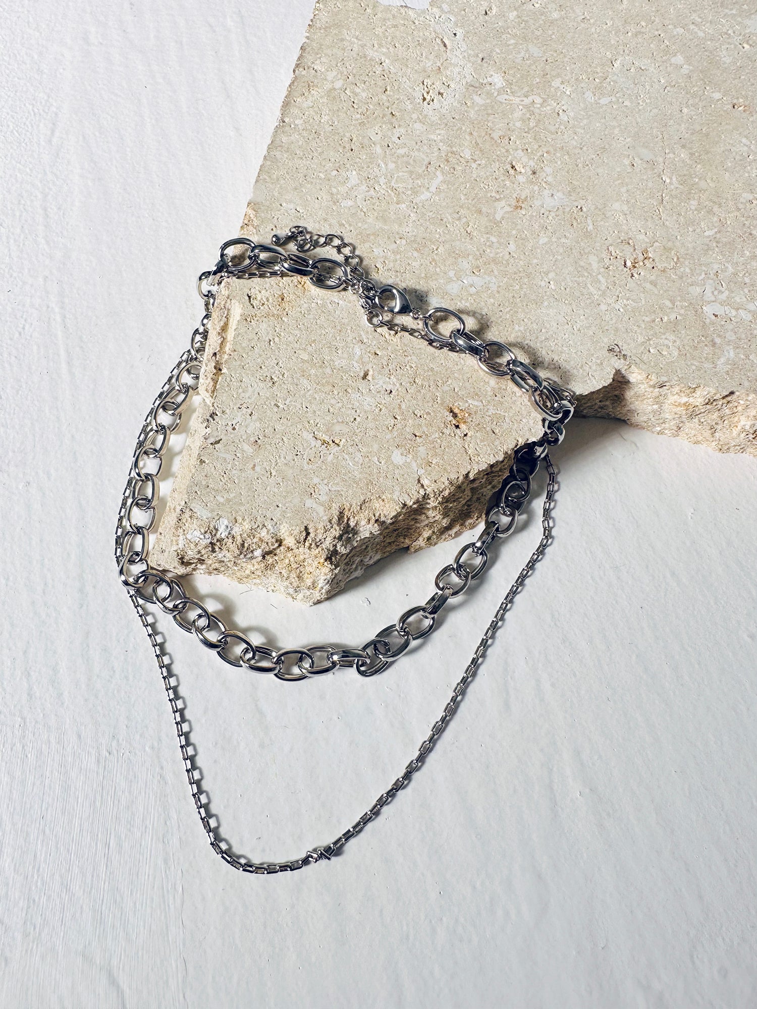 Resting atop a decorative stone, the Layered Chain Necklace steals the spotlight with its detailed view, accentuating the beauty of its intricate design.