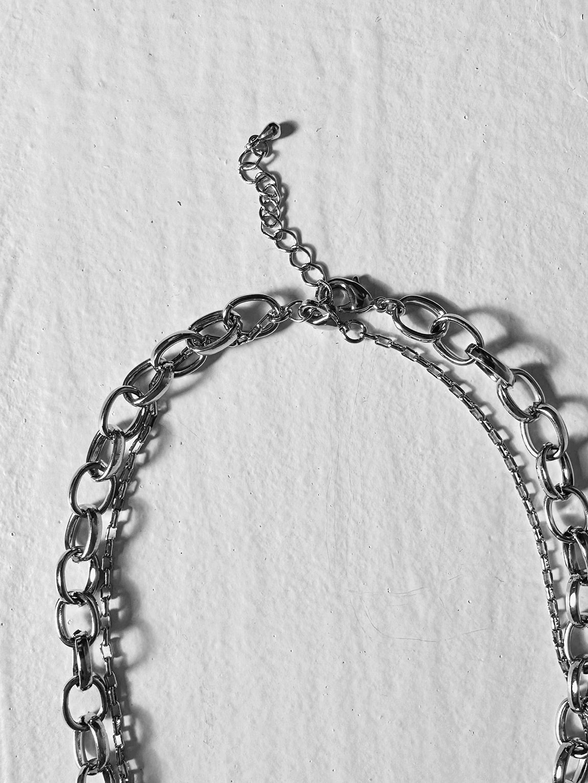 Zoomed in, a close-up of the Layered Chain Necklace reveals intricate details of its clasps and chains.