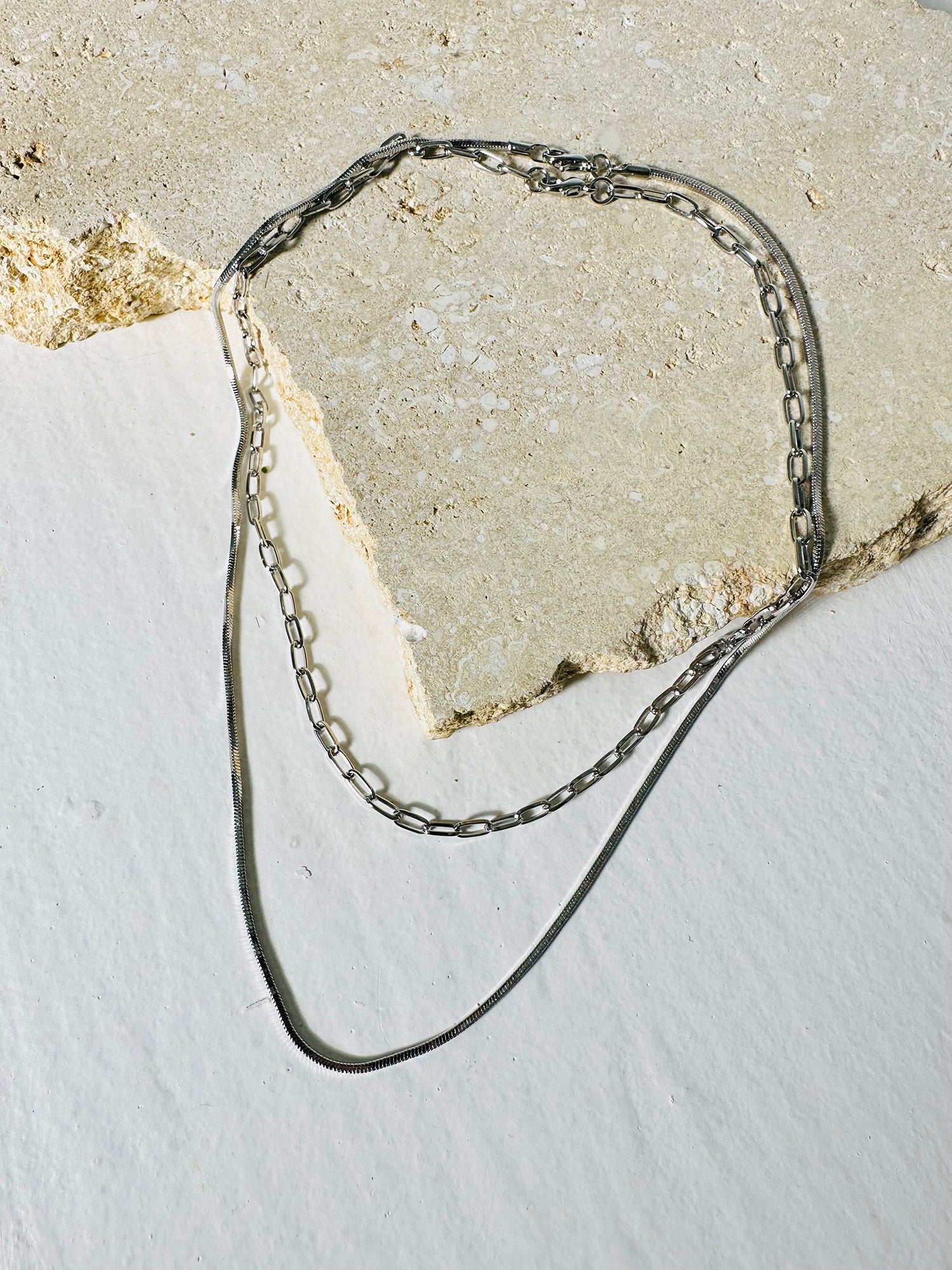 An aesthetically arranged photograph showcasing a stylish layered paperclip chain necklace.