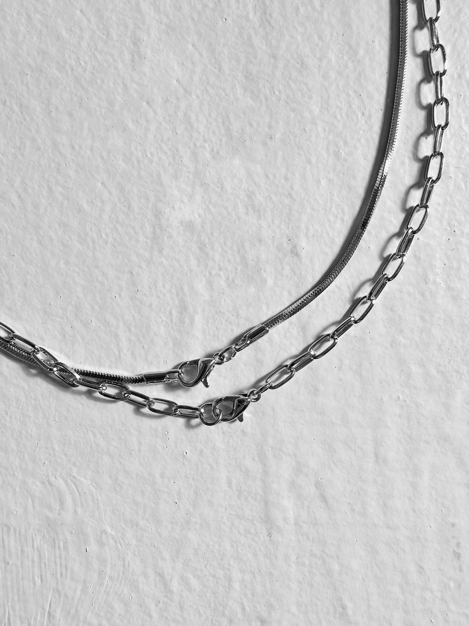 Zoomed in, a close-up of the Layered Paperclip Necklace reveals intricate details of its clasps and chains.