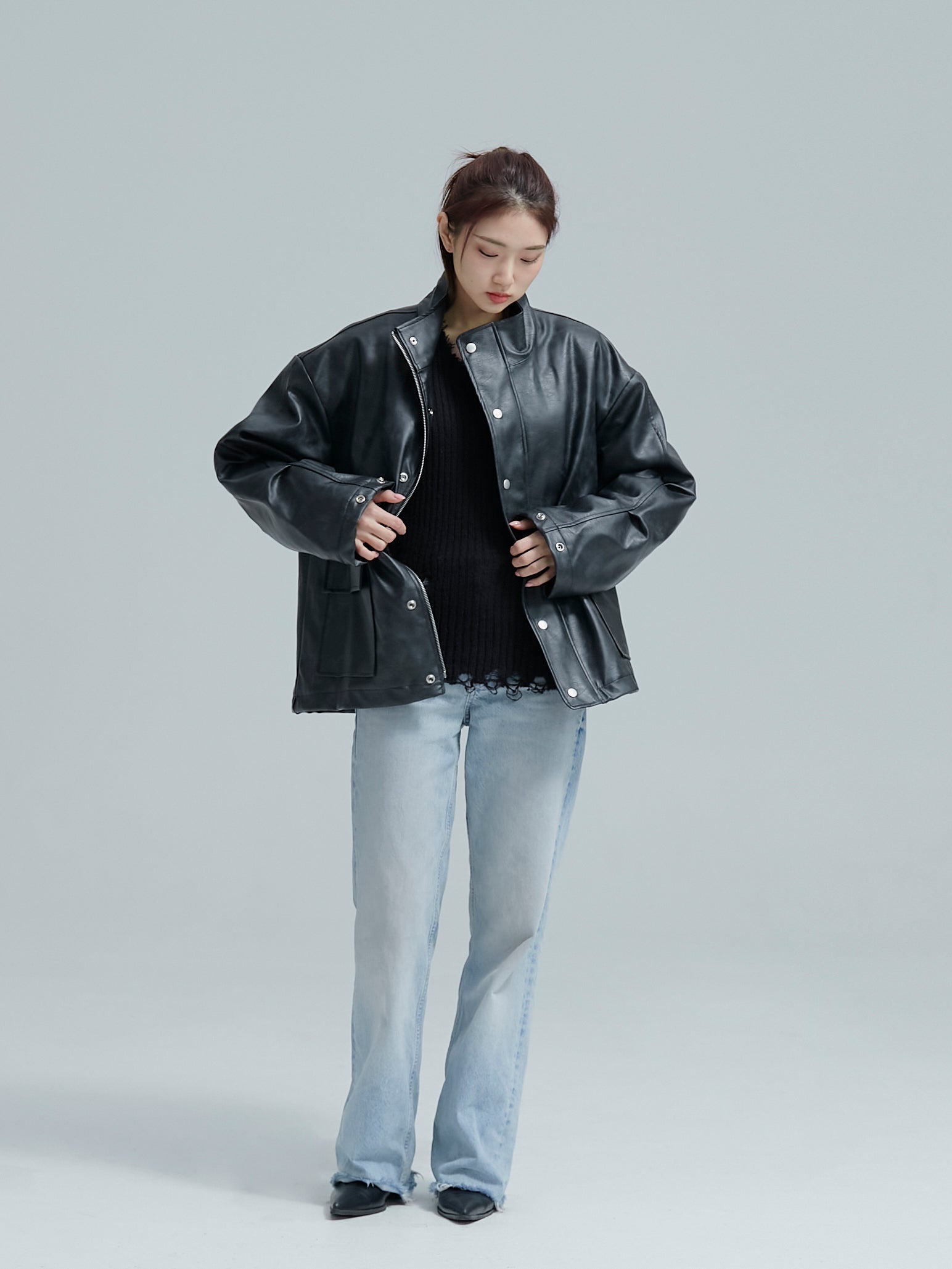  The model is wearing a Lined leather jacket and looking downward to highlight Korean street fashion.