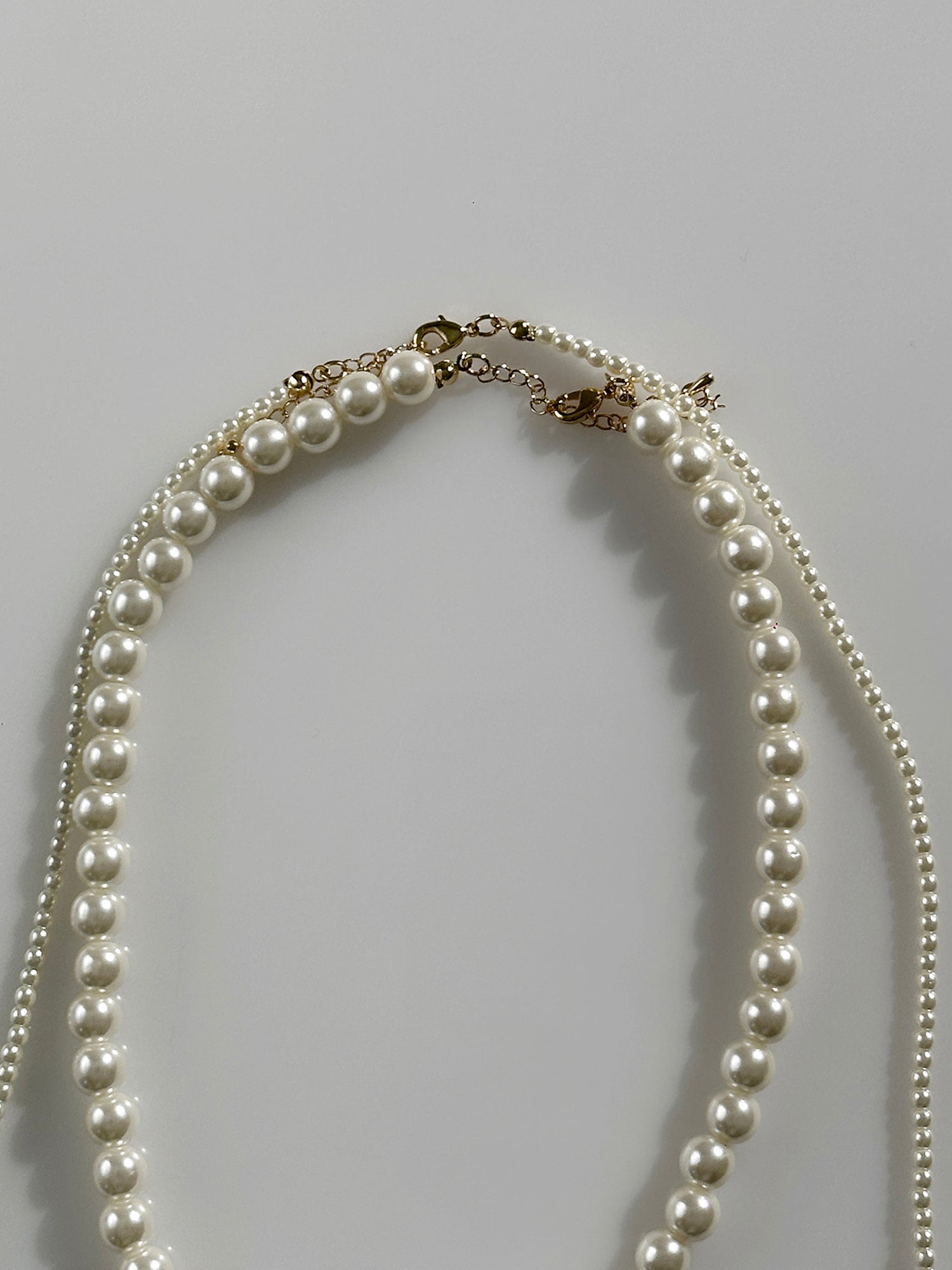 A close-up view of the long pearl strand necklace, highlighting the intricate design details and the materials used in its creation.